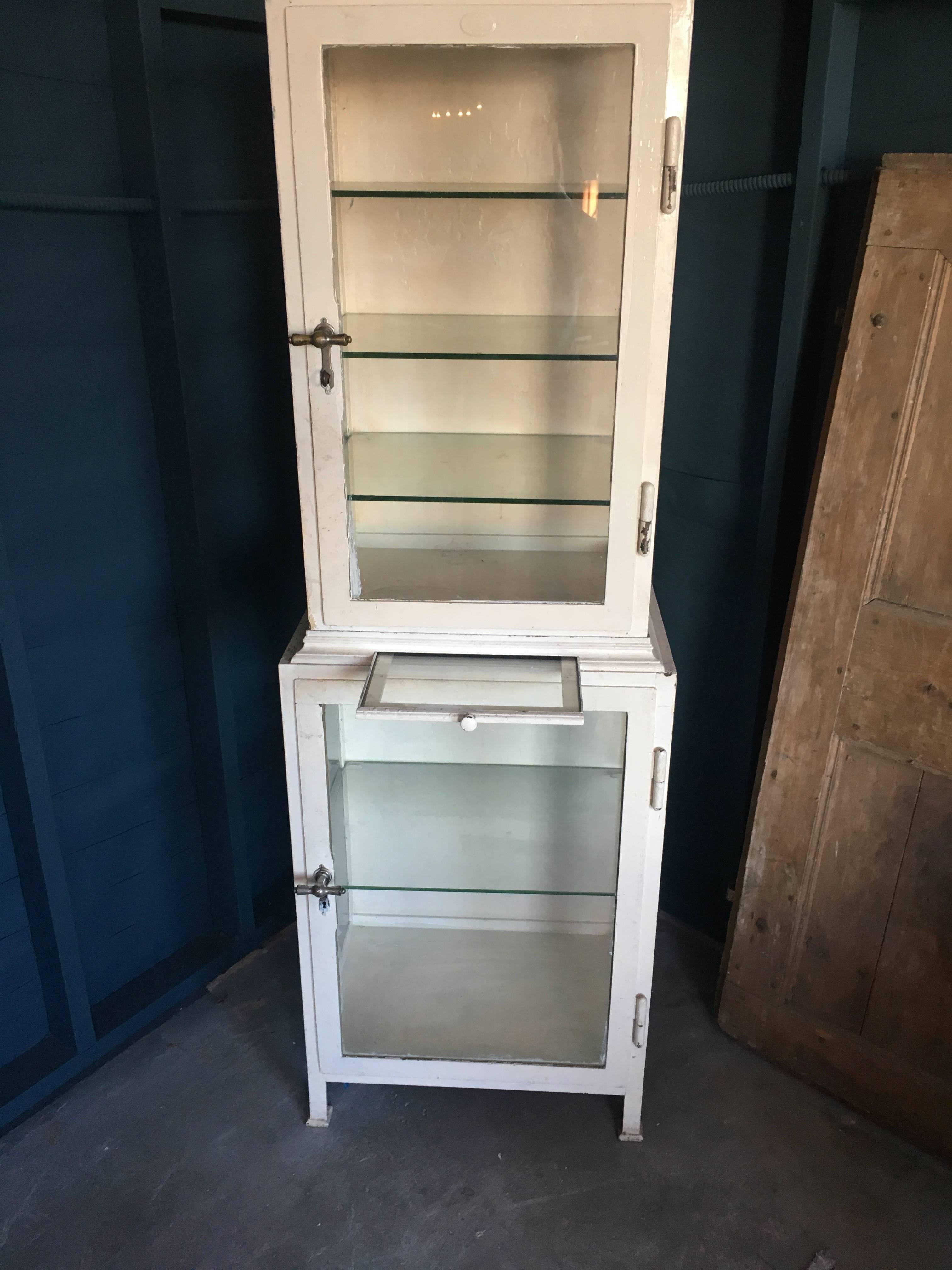 1920s painted European dentist cabinet. Features original hardware, glass cabinet doors, and glass shelves. Glass pull-out shelf measures 12