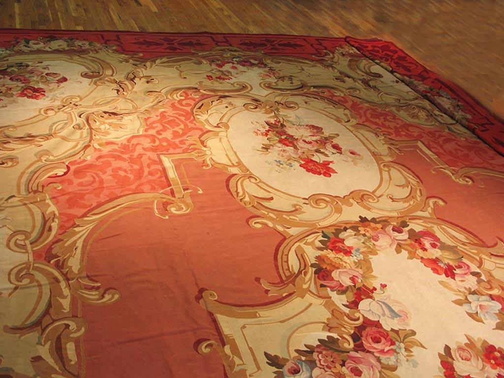 Die Webstühle von Aubusson, südwestlich von Paris, waren in der Lage, Teppiche von außergewöhnlicher Größe zu weben, und dieser ist perfekt für den großen Salon Ihres Schlosses. Der rosafarbene Grund zeigt kunstvolle, mit Girlanden gefüllte,