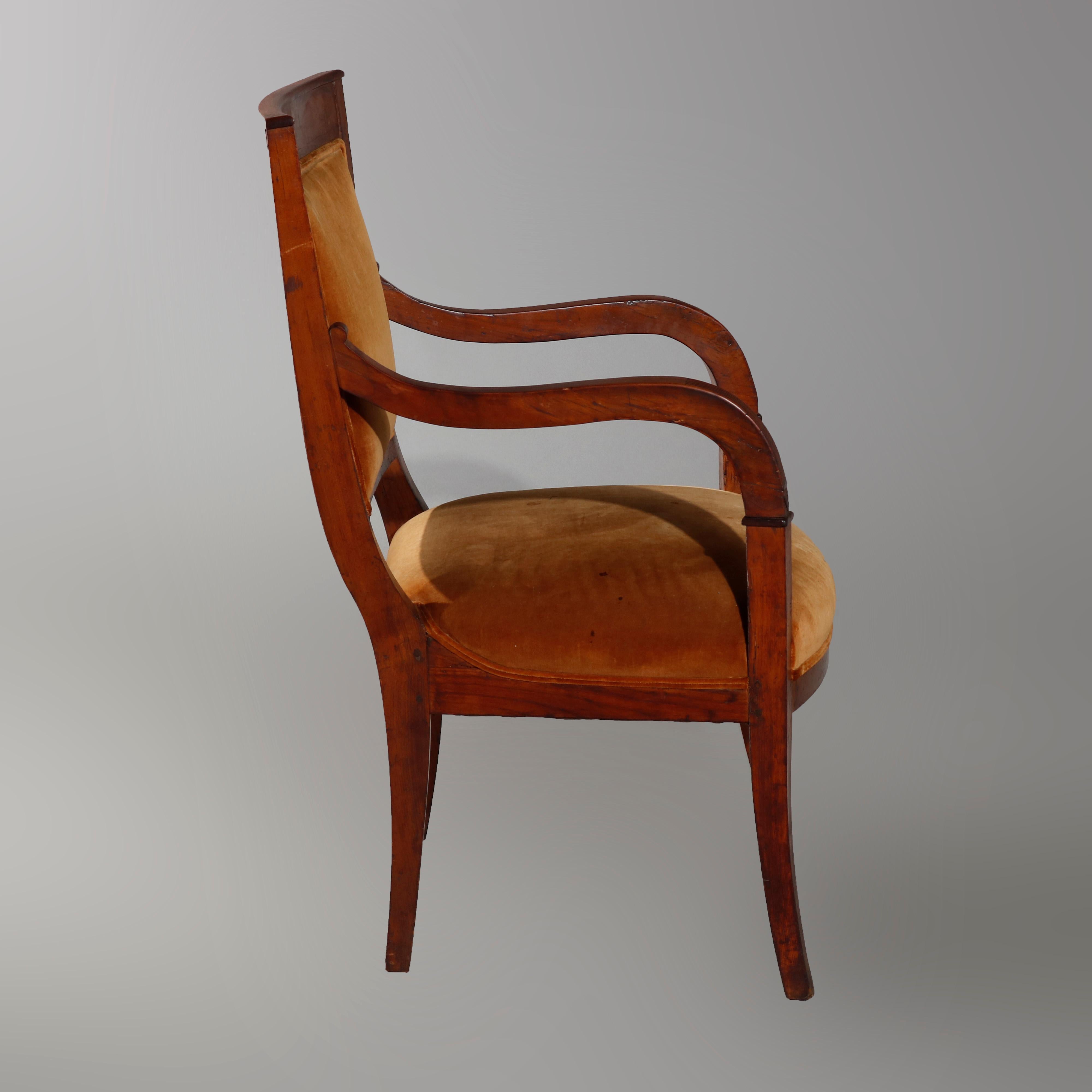 An antique Biedermeier armchair offers walnut frame with upholstered back and seat, S-scroll and reeded arms, raised on slightly flared and square legs, circa 1820

Measures: 35