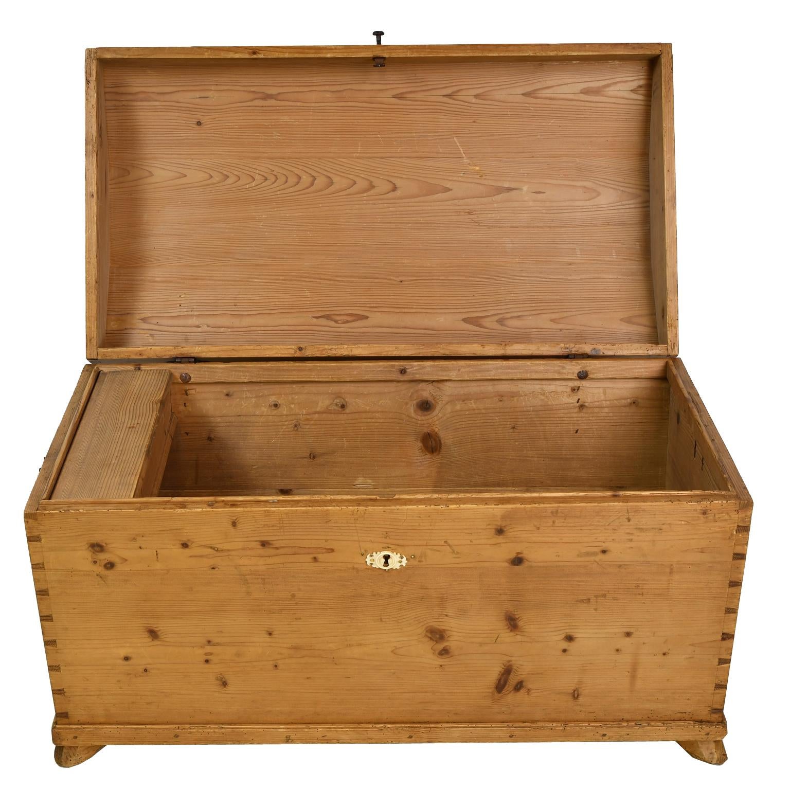 A lovely chest in pine with hinged dome-top over a tapered rectangular case with dove-tailed corners and resting on carved slipper feet. Interior offers a small lidded compartment that was used for the storage of gloves and other accoutrements.