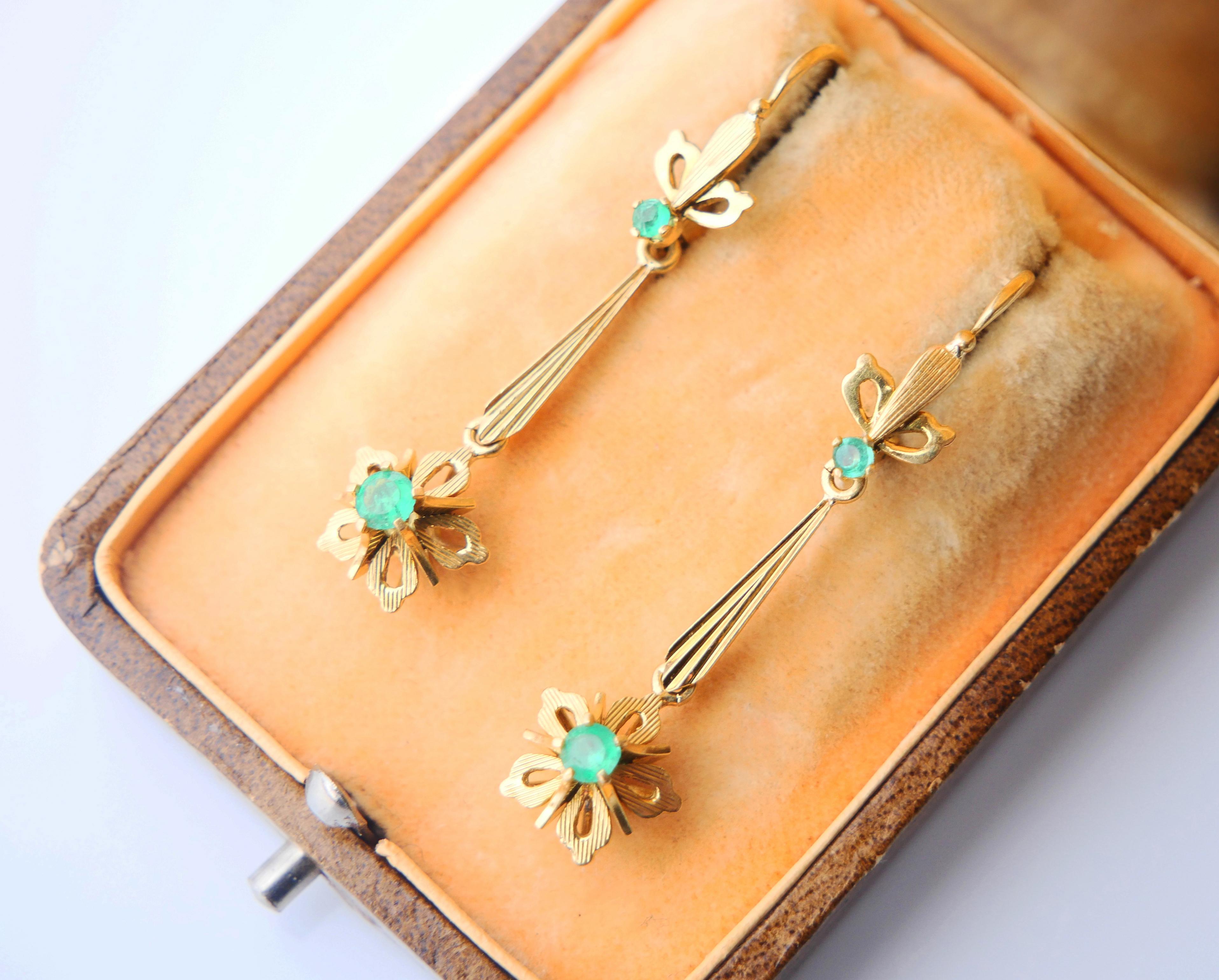 A pair of dangles with folding hooks in 18K Yellow Gold decorated with natural Emeralds settings. 

Both have 18K hallmarks . Hand - made in Europe ca. 1920 -1930s.

Each earring is 41 mm long 
Florets measure Ø10 mm x 8.5 mm deep. Larger Emeralds Ø