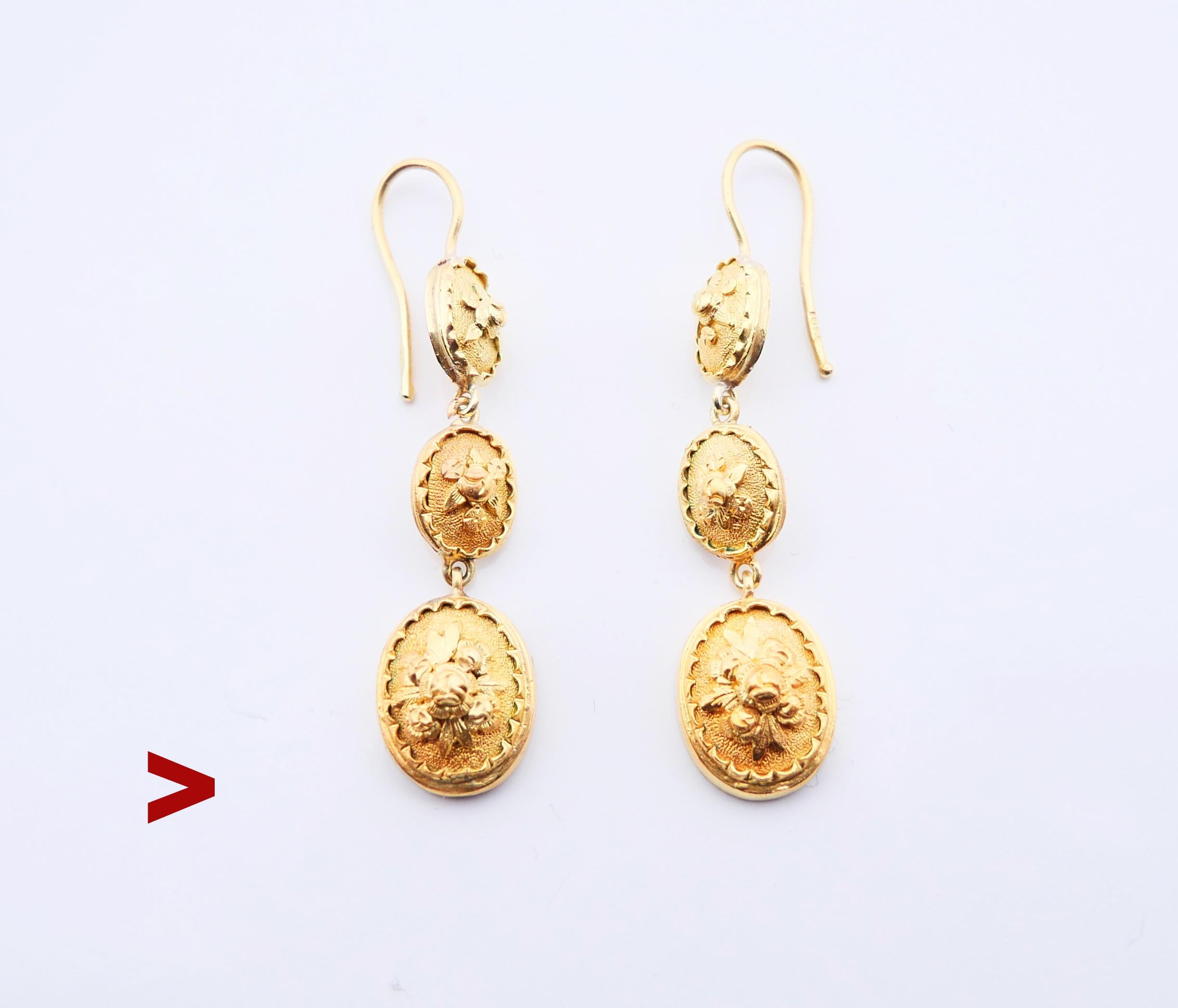 A pair of antique earrings with chained oval medallions of gradual sizes decorated with cast floral ornaments.

Made ca. early 1900s. Hooks hallmarked 18K , metal tested solid 18K Yellow Gold.

Each earring is 47 mm long suspended. Oval dangles are