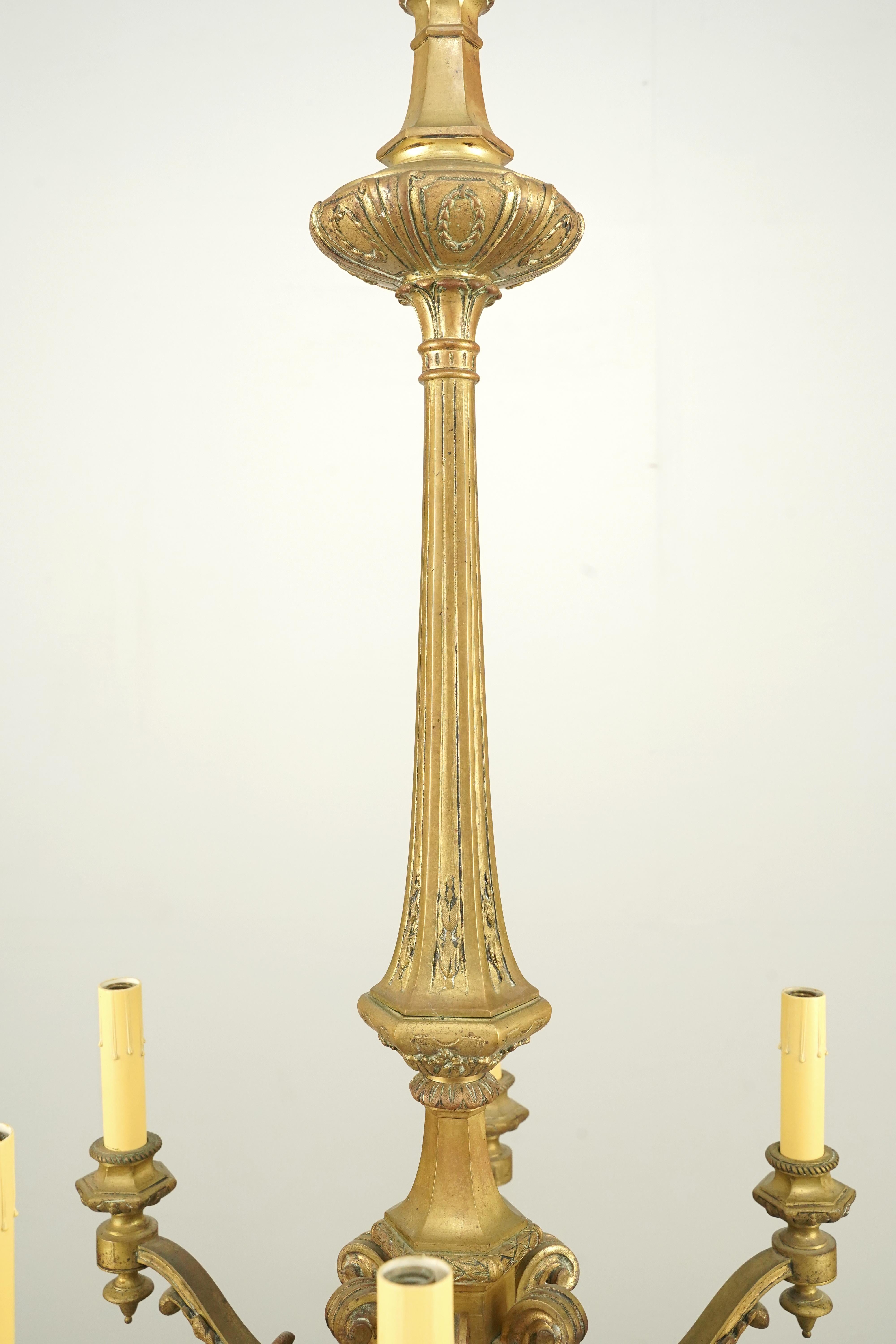 Araña de bronce de estilo francés, con un vástago central de acero con elementos decorativos, incluidos motivos de hojas de acanto en los brazos y una cadena de acero. Esta luz requiere seis bombillas candelabro E-12. Limpiado y restaurado. Buen