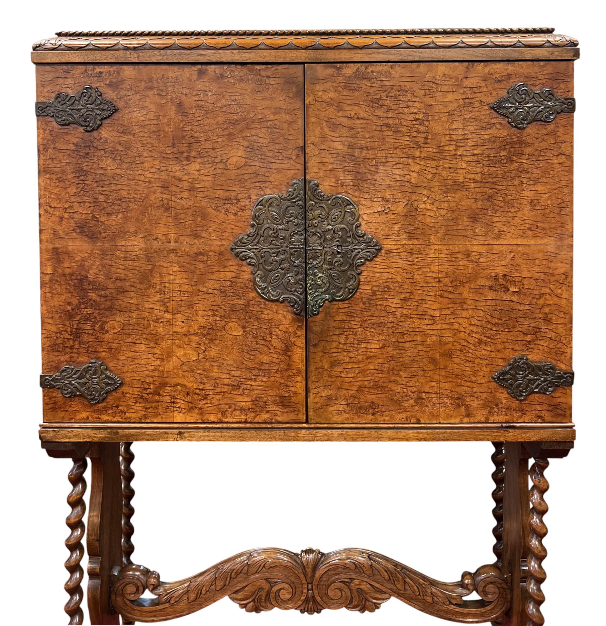 This distinctive piece fuses Moorish and Iberian influences characteristic of Spanish or Portuguese, circa the second half of the 19th century, featuring a veneer burl wood finish, ornate corner mounts and a central escutcheon.
The cabinet rests on