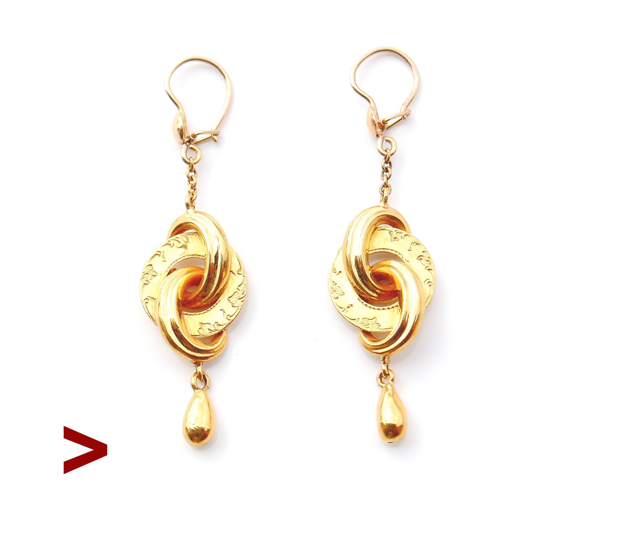 Ein Paar antike Ohrringe mit Körpern in Form von verketteten Scheiben oder ewigen Knoten aus massivem 18-karätigem Gelbgold mit frei hängenden tropfenförmigen Anhängern.

Jede der drei Scheiben hat ein Volumen und alle drei sind innen hohl, die