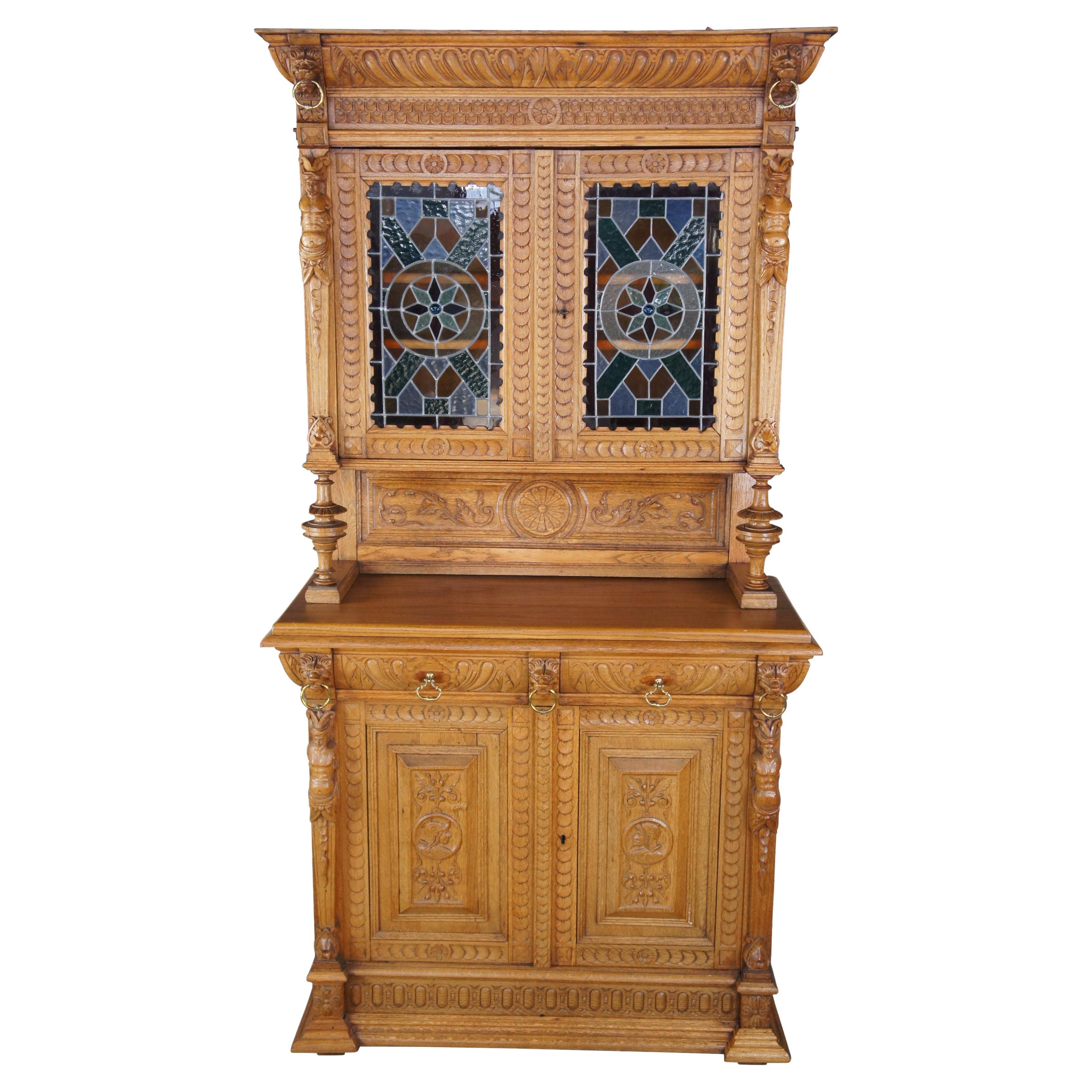 Monumental Antique Mechelen Renaissance Revival China Hutch, circa 1890s.  Made from oak with elaborate figural and floral carved details.   Features vibrant original stained glass windows.  The buffet or server section of the cabinet has a large
