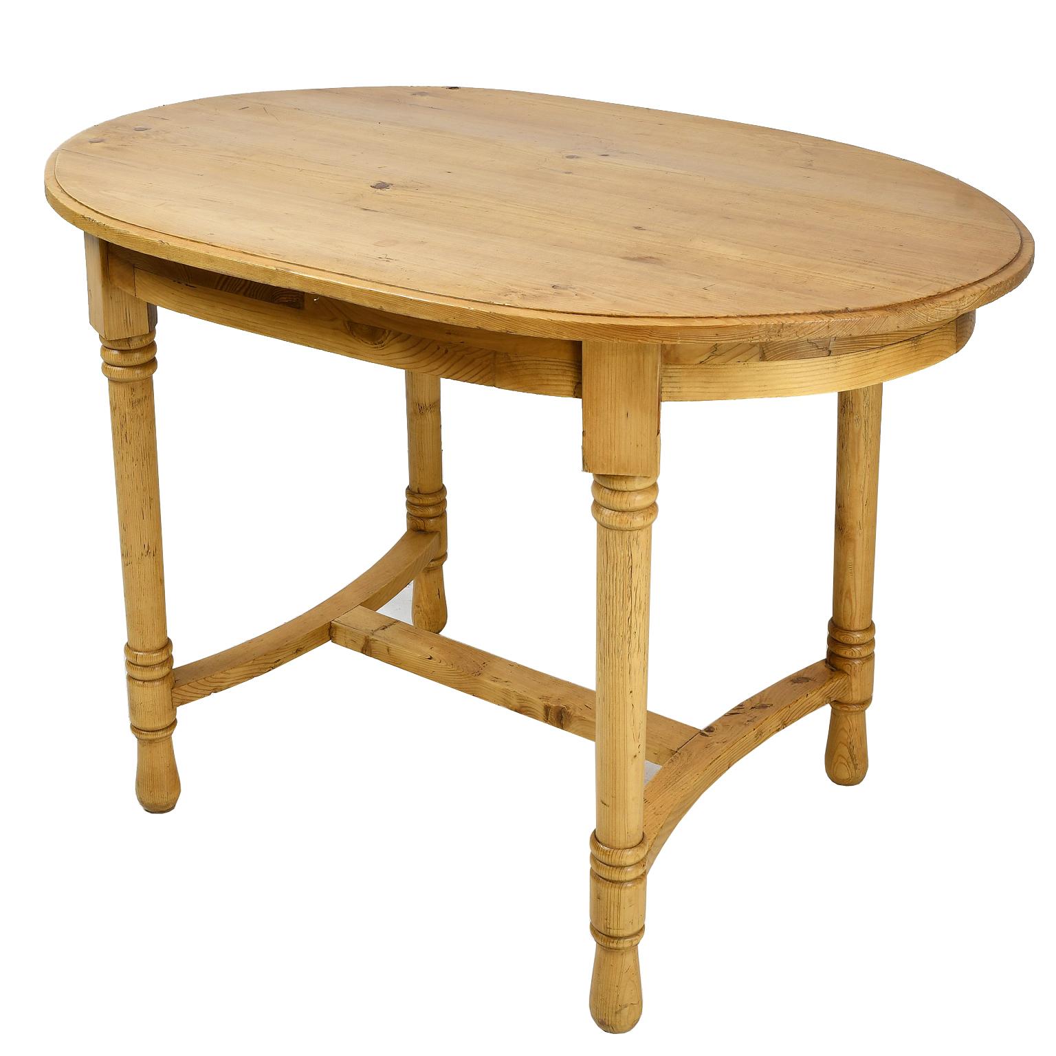A Danish or North German oval table in scrubbed pine with a traditional wax finish that showcases the light honey-color of the wood. Oval top rests on an apron over four turned legs with 