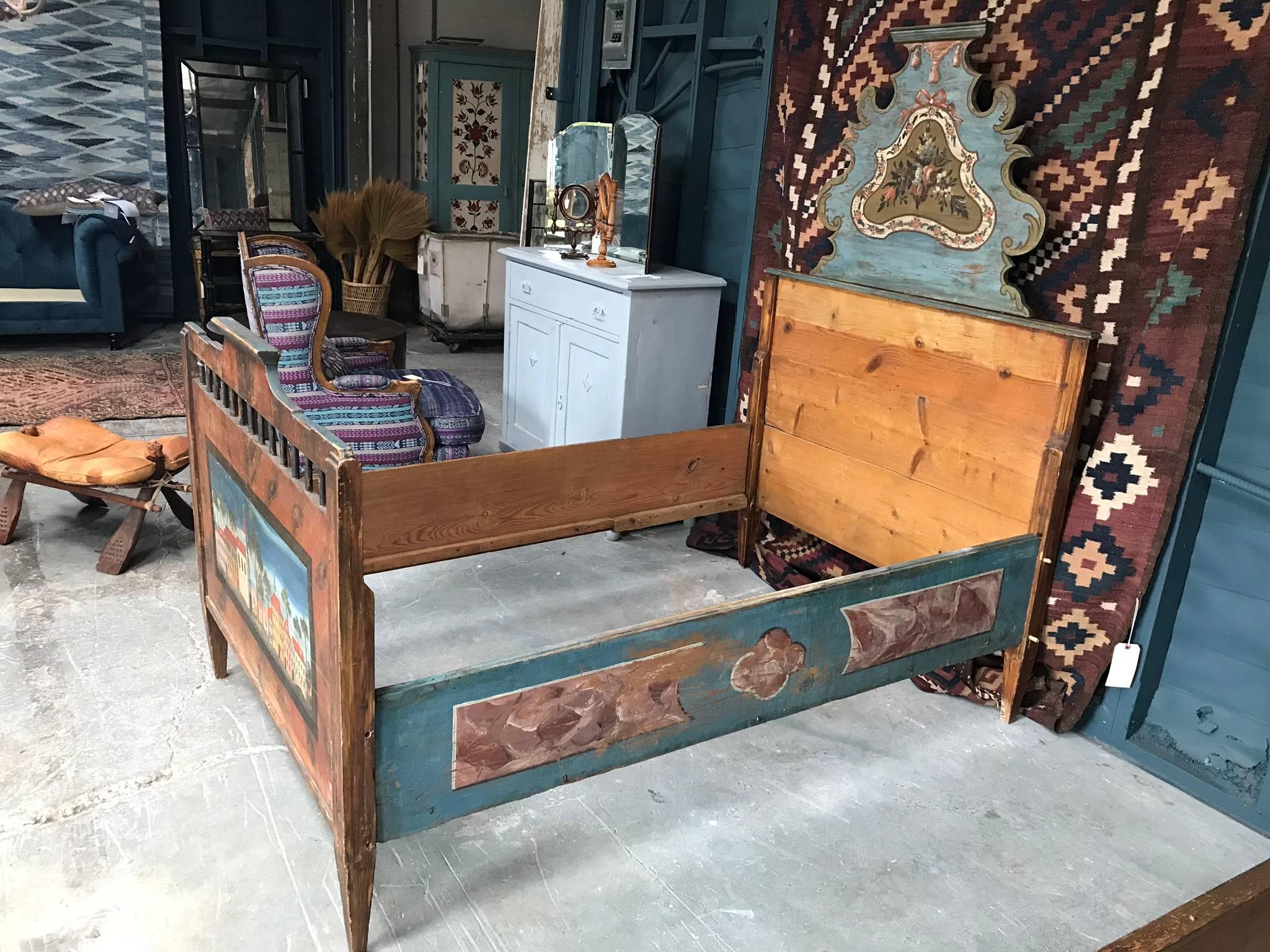 Late 19th century children's bed frame in oak. Features a hand-painted scene of a town square, tapered legs and handcrafted wood decorative detailing.