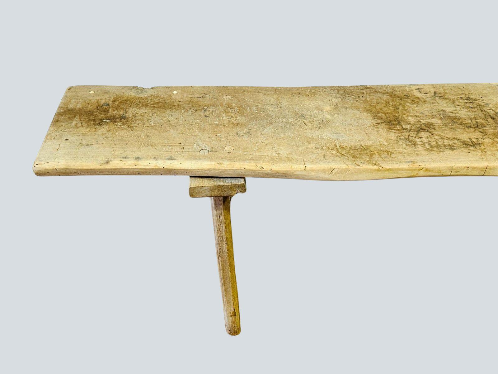 A rare and character-rich antique European butcher’s bench, beautifully aged and bleached to highlight its organic textures. Crafted from solid wood with a naturally worn patina, this primitive three-legged bench was originally used for traditional