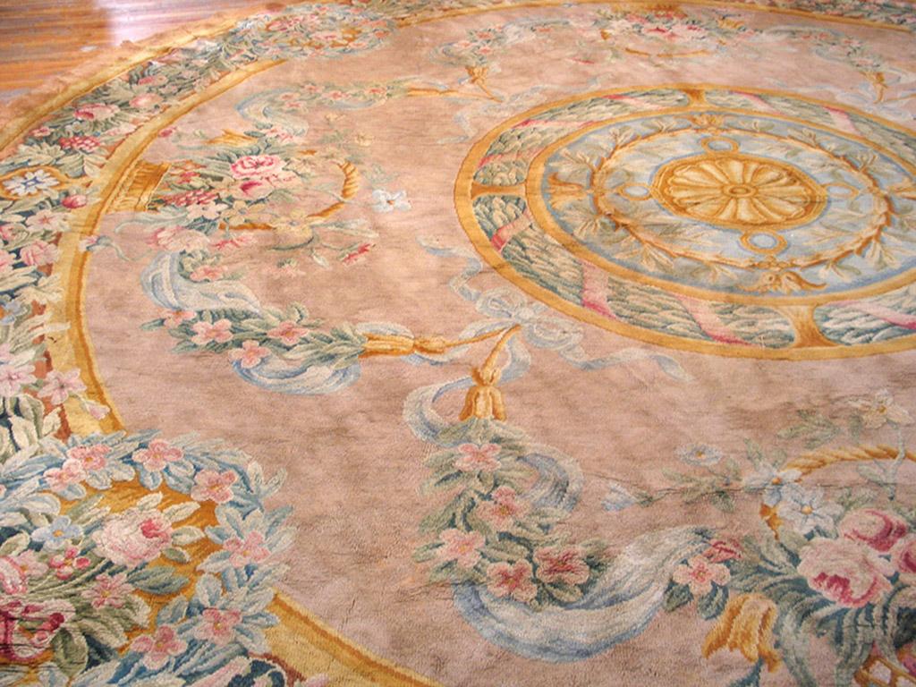 Large, round antique high pile Savonneries carpets are rare. The four-layer round medallion shows a rosette, laurel leaves and ribbons, and loops, on a tan ground decorated with basket-bouquets and flowering garlands. Densely packed wreaths