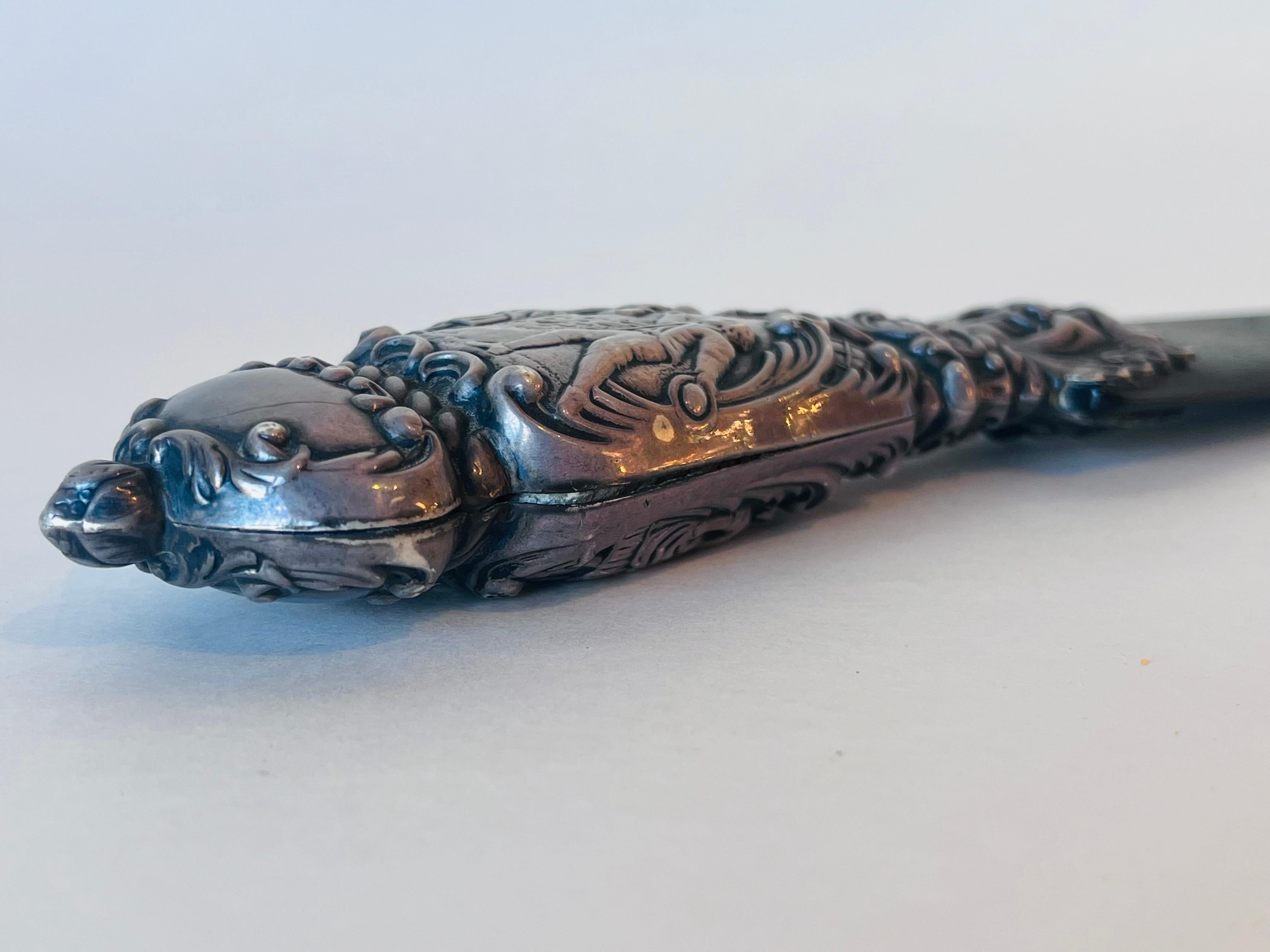 A monumental - sixteen inches long - antique European, probably English, silver and tortoise shell page turner or paper knife. The repousee handle has a smiling face surrounded by a detailed crown of foliate design. There are then a few bands of