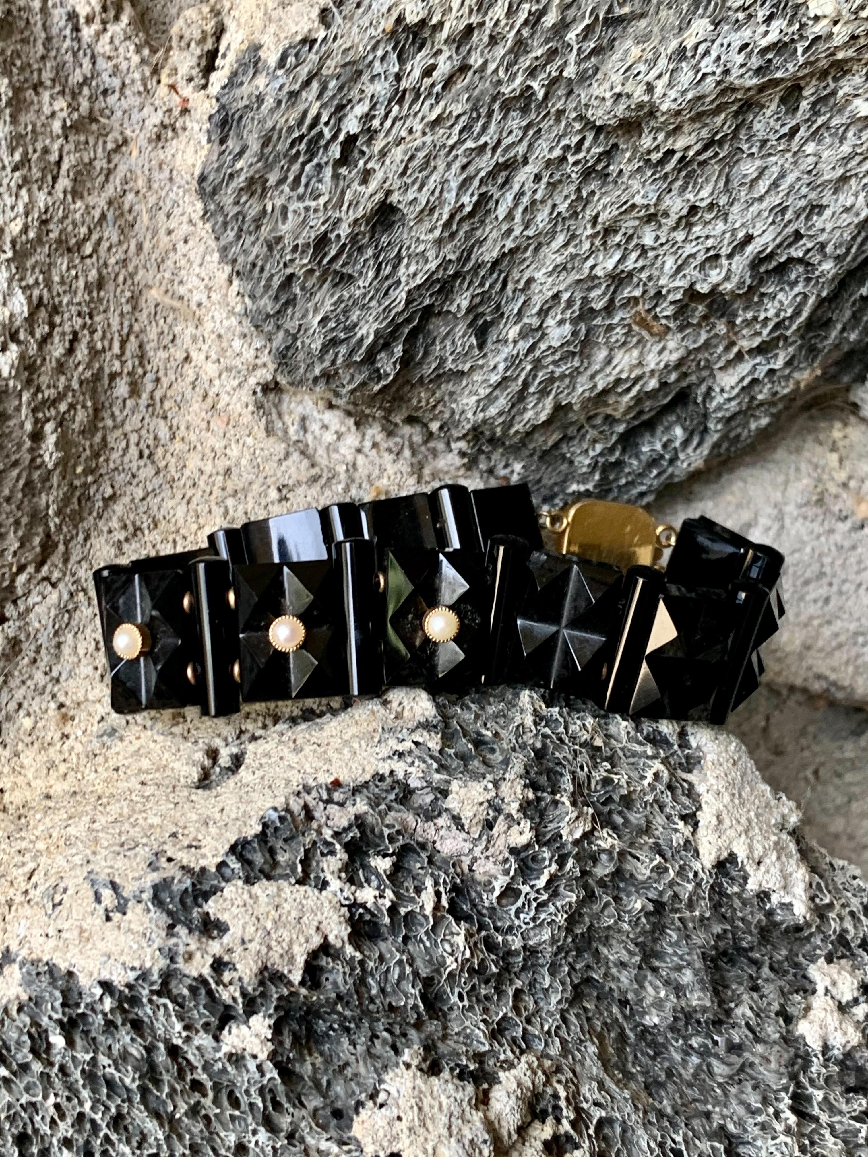 This stunning antique bracelet features eleven links of black Onyx with cylinder-shaped black Onyx spacers.  There are three pearls used to accent the bracelet.  They are each set in 14k yellow Gold.  Each Pearl is 3.5mm is size.

The clasp is