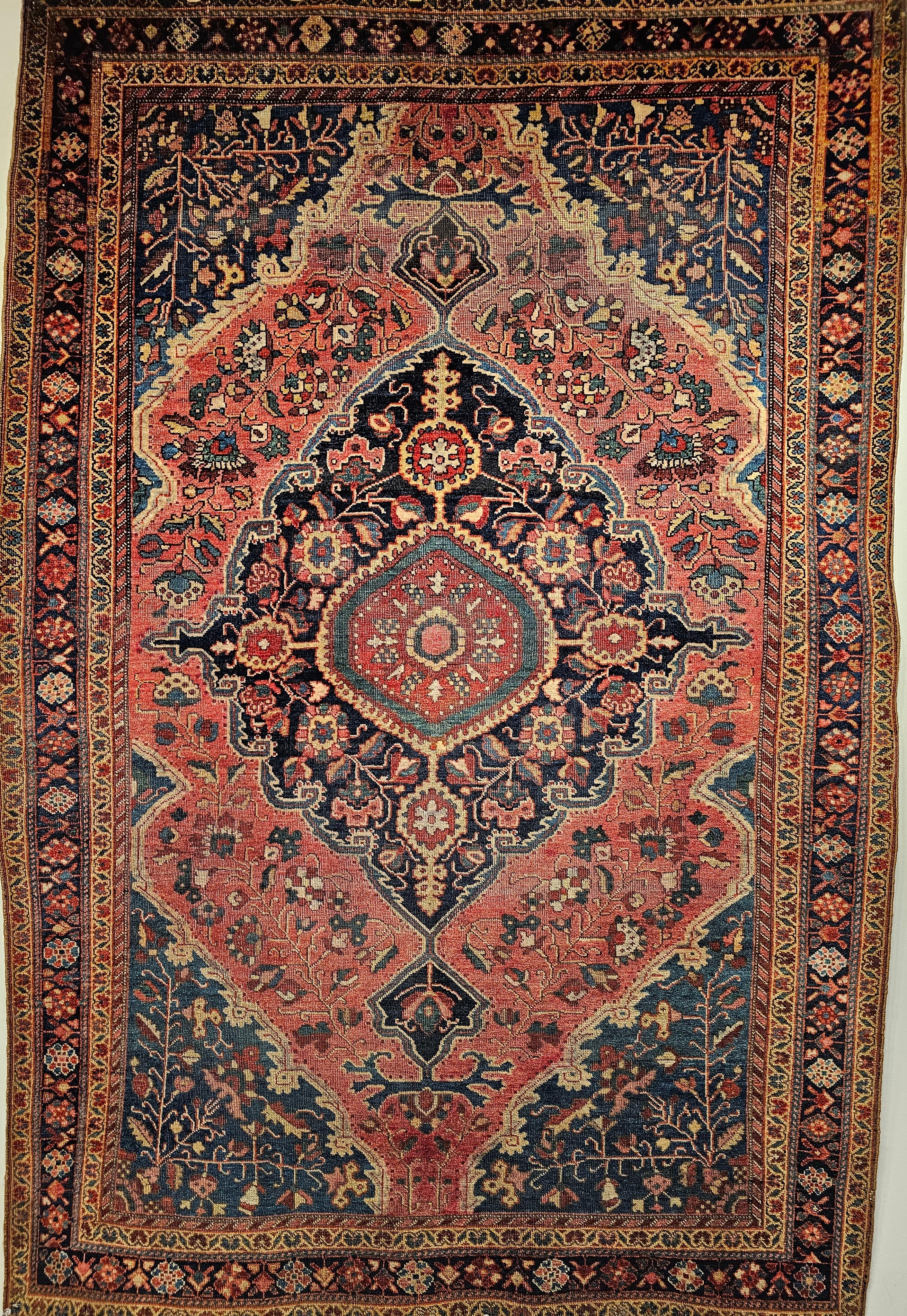 Wonderful 19th Century Persian Farahan Sarouk area rug in floral pattern with rust red, French blue, and navy blue colors.  The field is in pink or rust red color with a central medallion in navy blue. The overall floral design of the rug is