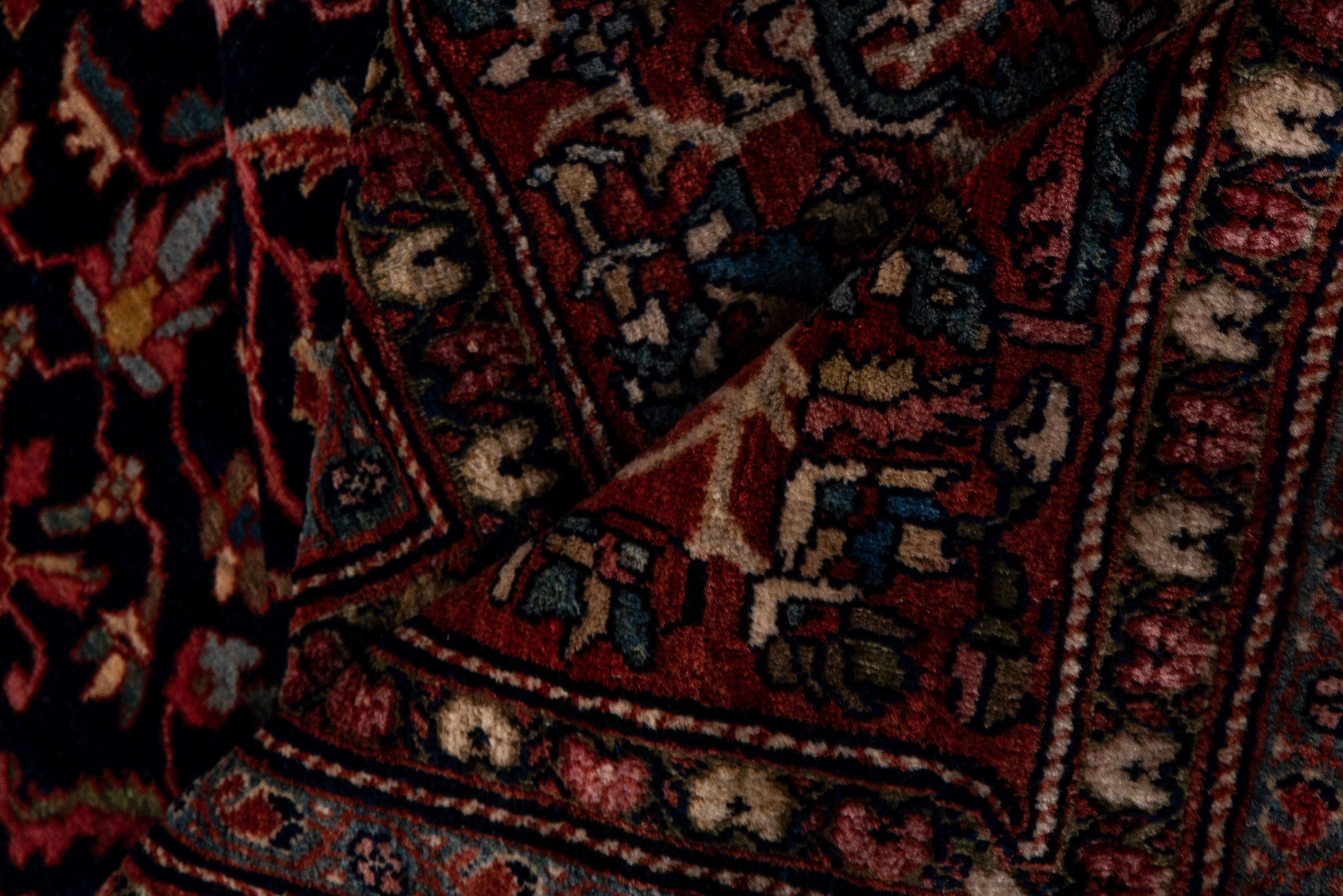 No medallion or large central motif, but a very dense, small all-over pattern of tiny palmettes, diminutive rosettes and tiny leaves closely covers the midnight navy ground, framed by a red border of ivory vinery sections entangling palmettes. Great