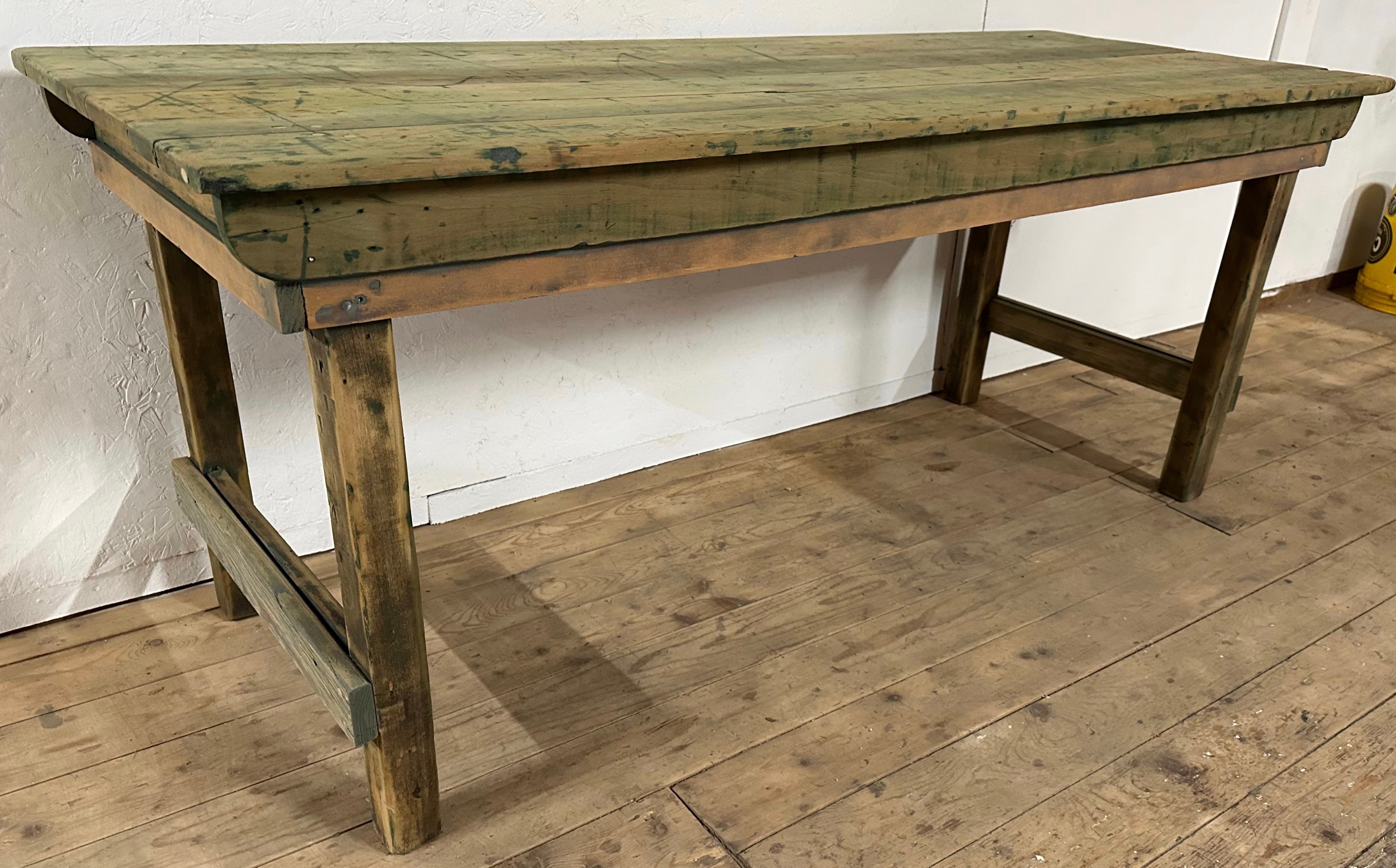Cette table de récolte rustique et ancienne, autrefois peinte, a conservé une grande partie des résidus de la peinture d'origine, ce qui lui confère charme et caractère.  Le plateau de table en planches offre une couleur et un ton riches et chauds
