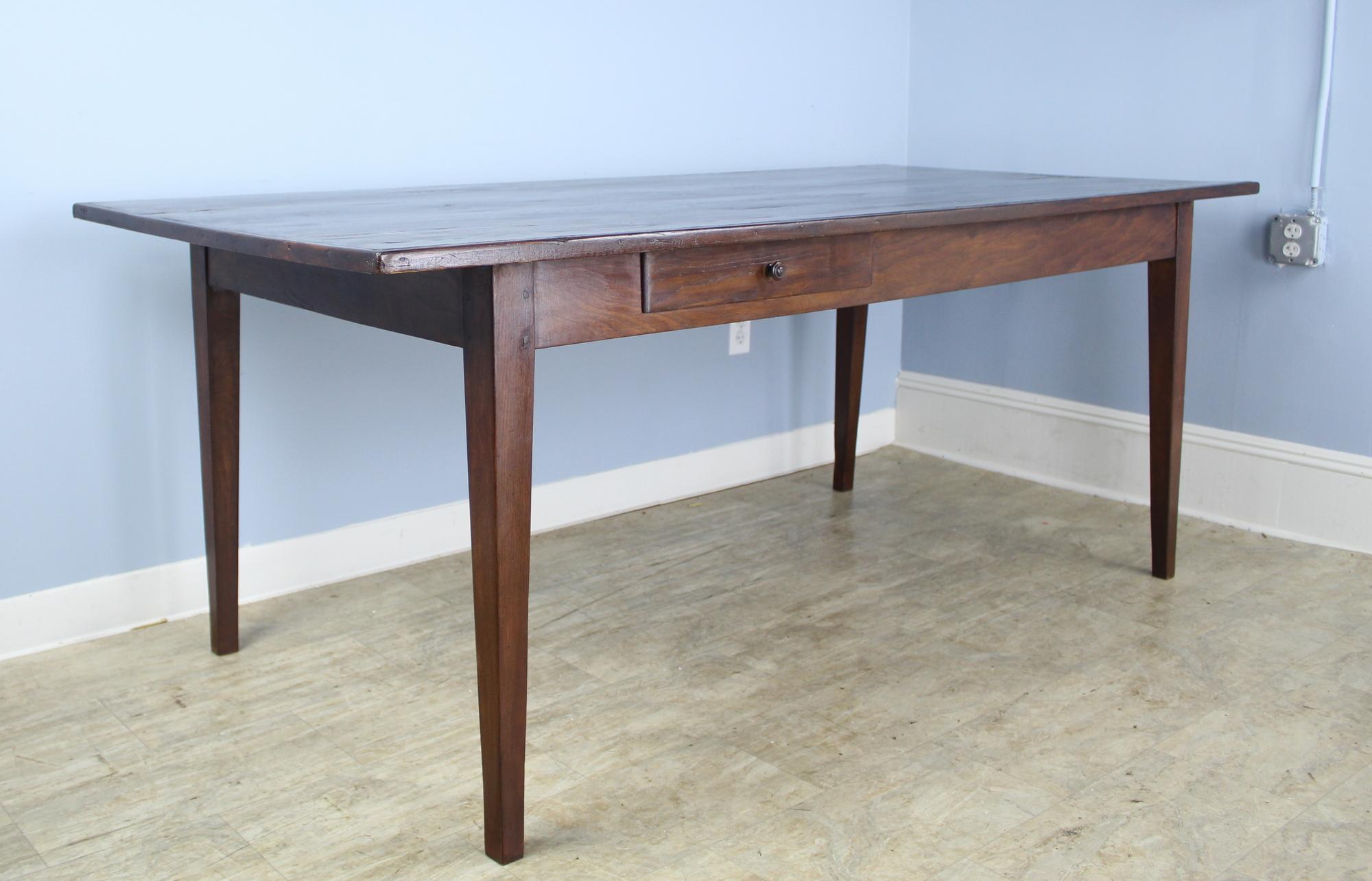 A fabulous dark farm table with many desirable features. It is nice and deep for an antique table so lots of room for platters in the center. The top has a lovely grain pattern and is trimmed with a traditional decorative edge. With 62 inches