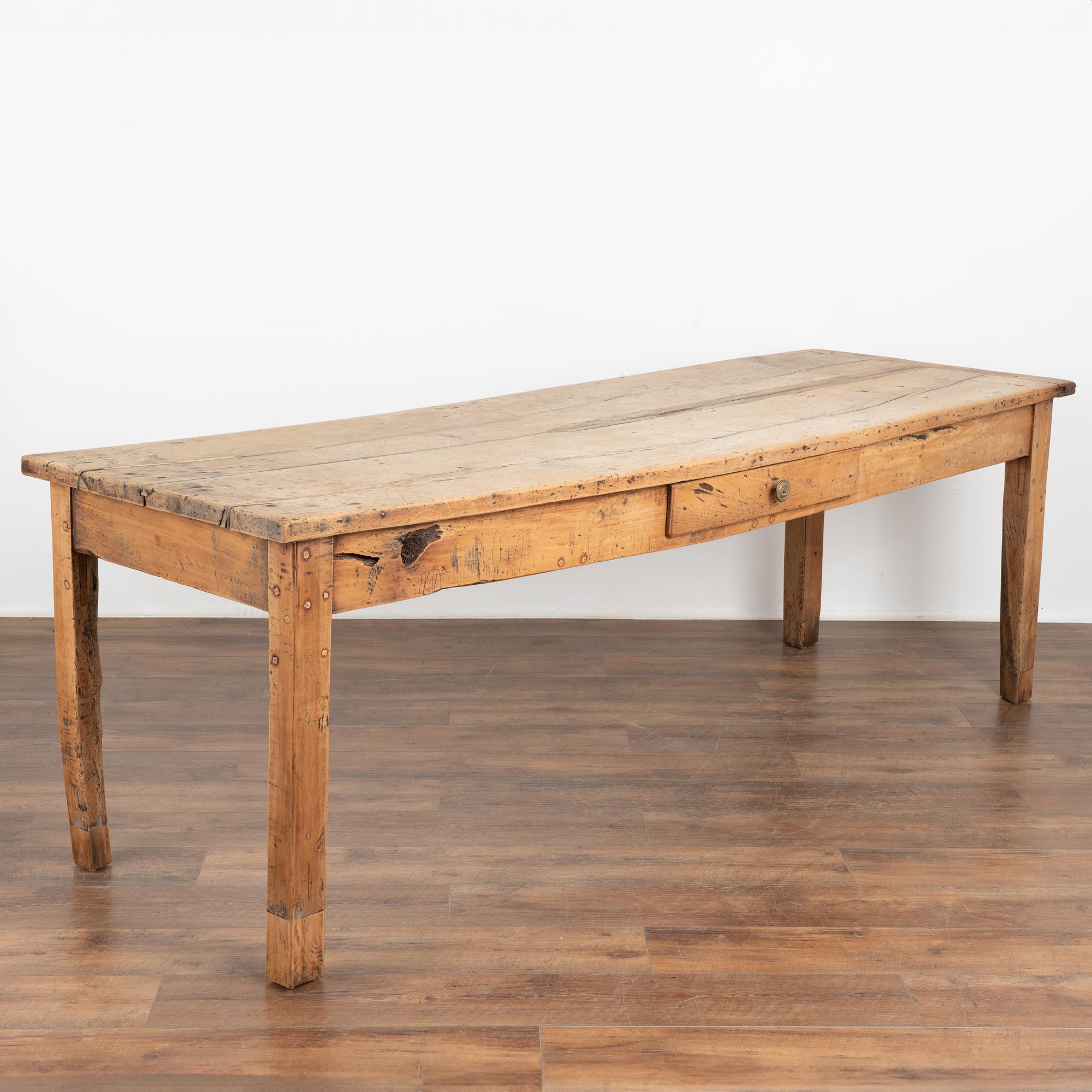 The beauty of this old farm table comes from the the generations of use seen in every nick, crack, old repair, knot hole and more which all adding to its the worn appeal.
A single drawer is located on each side of the table (one in center, one set