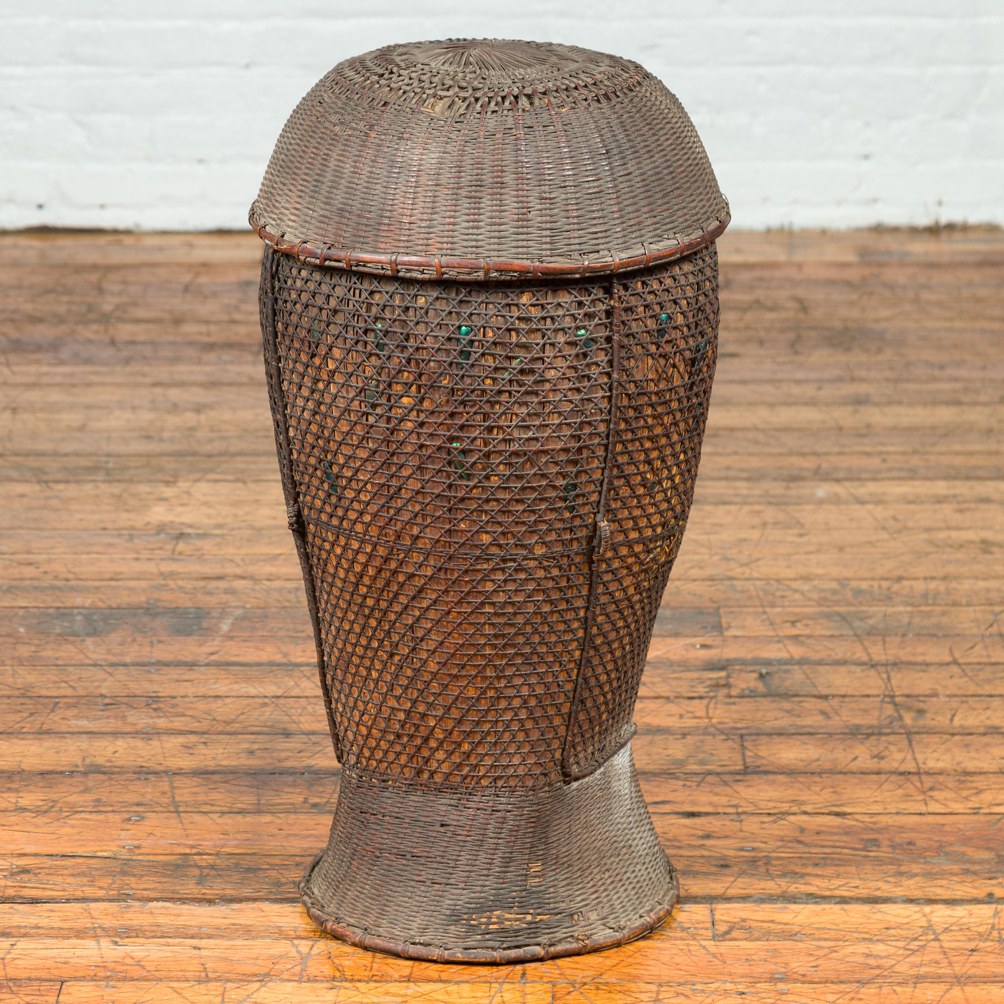 An antique farmer's grain basket from the 19th century, with cylindrical silhouette, iridescent motifs and lid. This 19th-century antique farmer's grain basket from the Philippines is an embodiment of rustic charm and utilitarian history. The basket