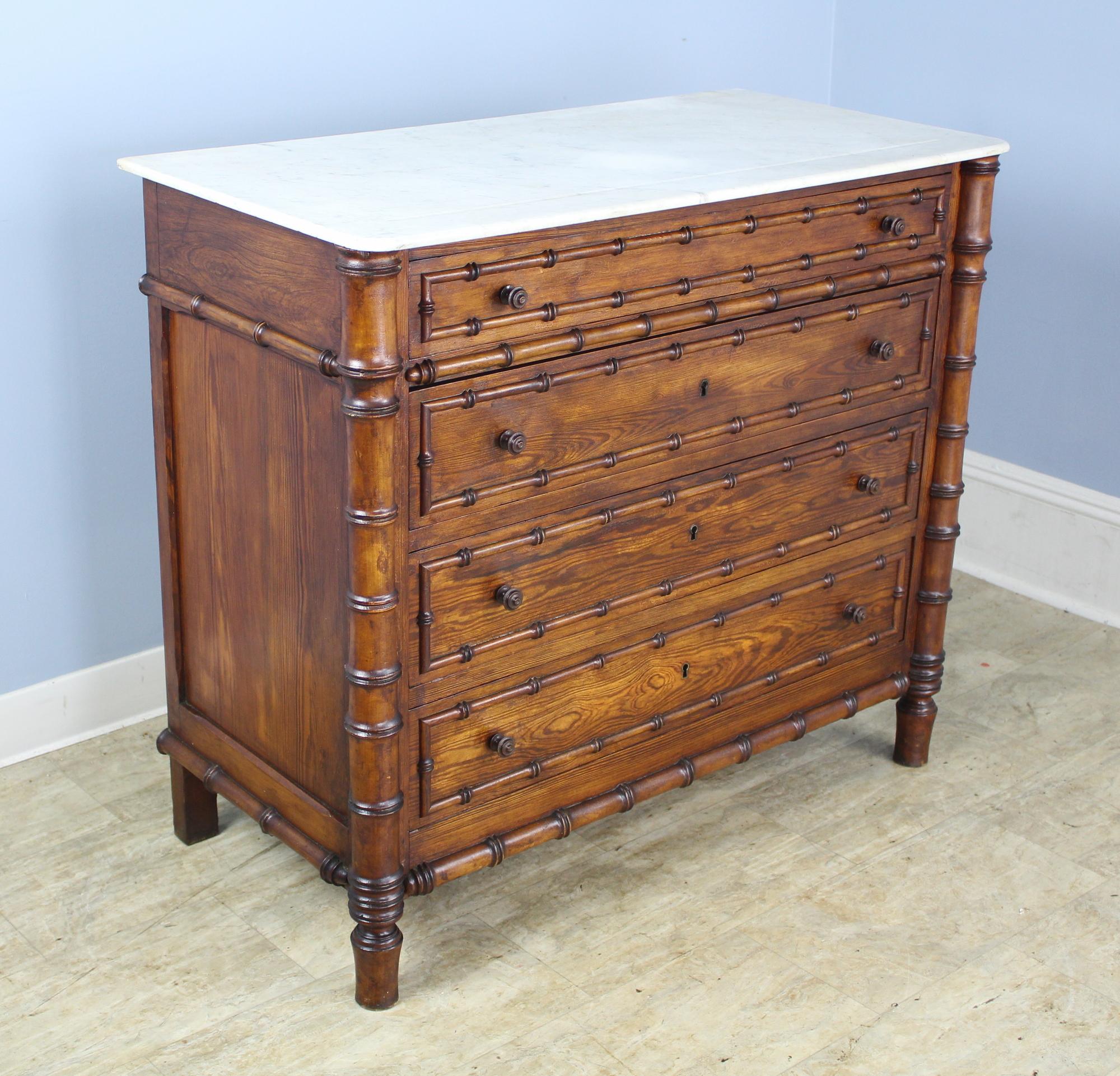A charming chest of drawers with faux bamboo columns and mouldings. Four roomy drawers. The marble which is original is in good antique condition. There is a small crack at the back of the marble which has been repaired. The key opens all three