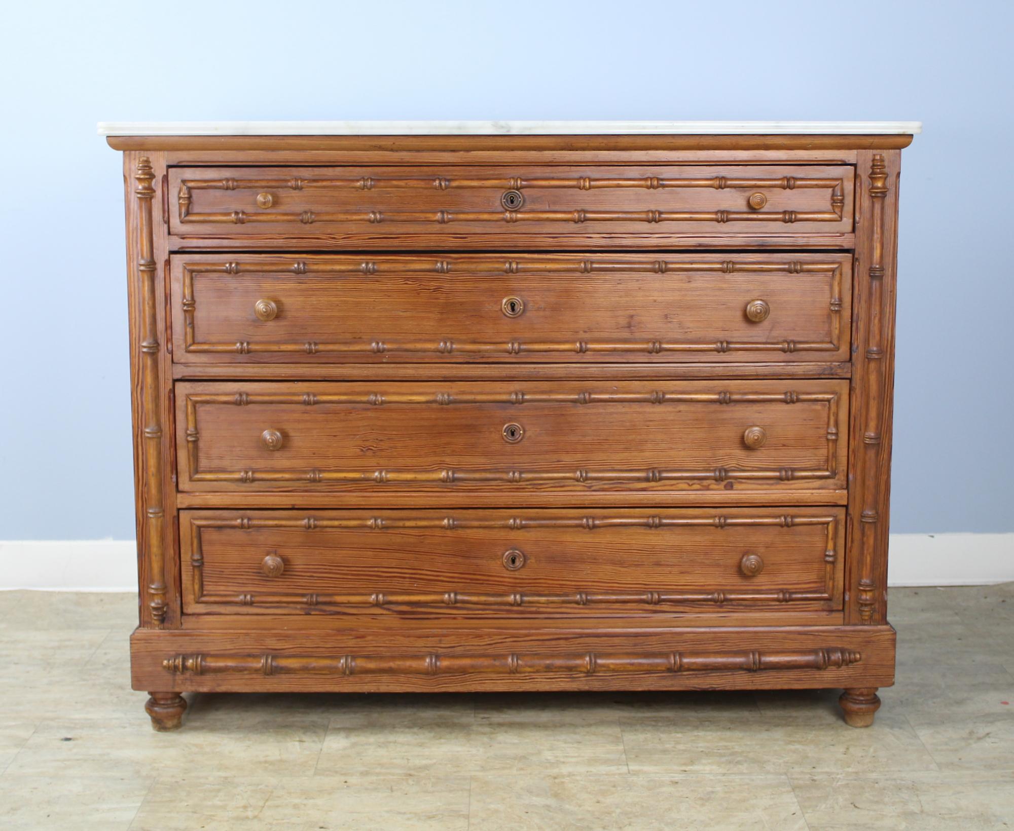 A charming large pine chest of drawers with faux bamboo columns and mouldings. Four roomy drawers. The interiors of the drawers have been painted so are clean. The marble which is original is in good antique condition, with the exception of some