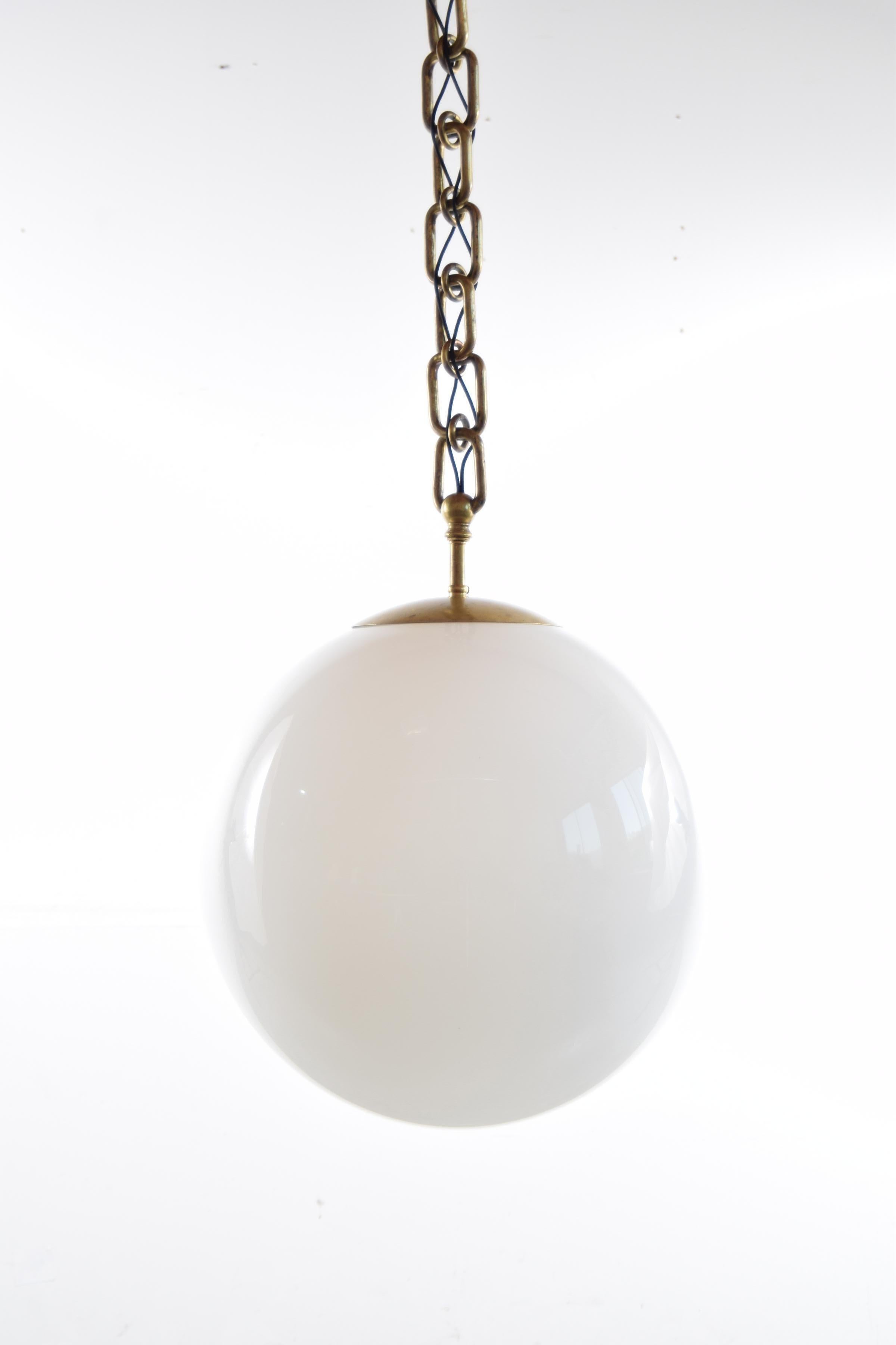 Unique antique lighting fixture, comprised of a sixteen inch diameter, hand blown milk glass sphere suspended from a faux brass chain. We paired the two together. The brass fixture has a patent date of 1908 stamped on it. The sixteen inch diameter