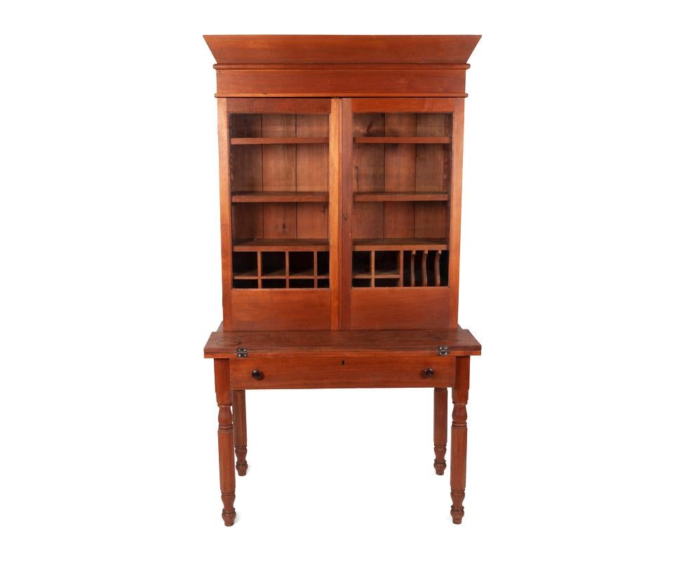 A Late Federal Cherrywood Desk and Bookcase, Circa 1830. 
This unique piece includes a folding desk and make a fabulous looking compact desk with plenty of storage in bookcase above. This was possibly a clerk's desk. 
Includes plenty of storage and
