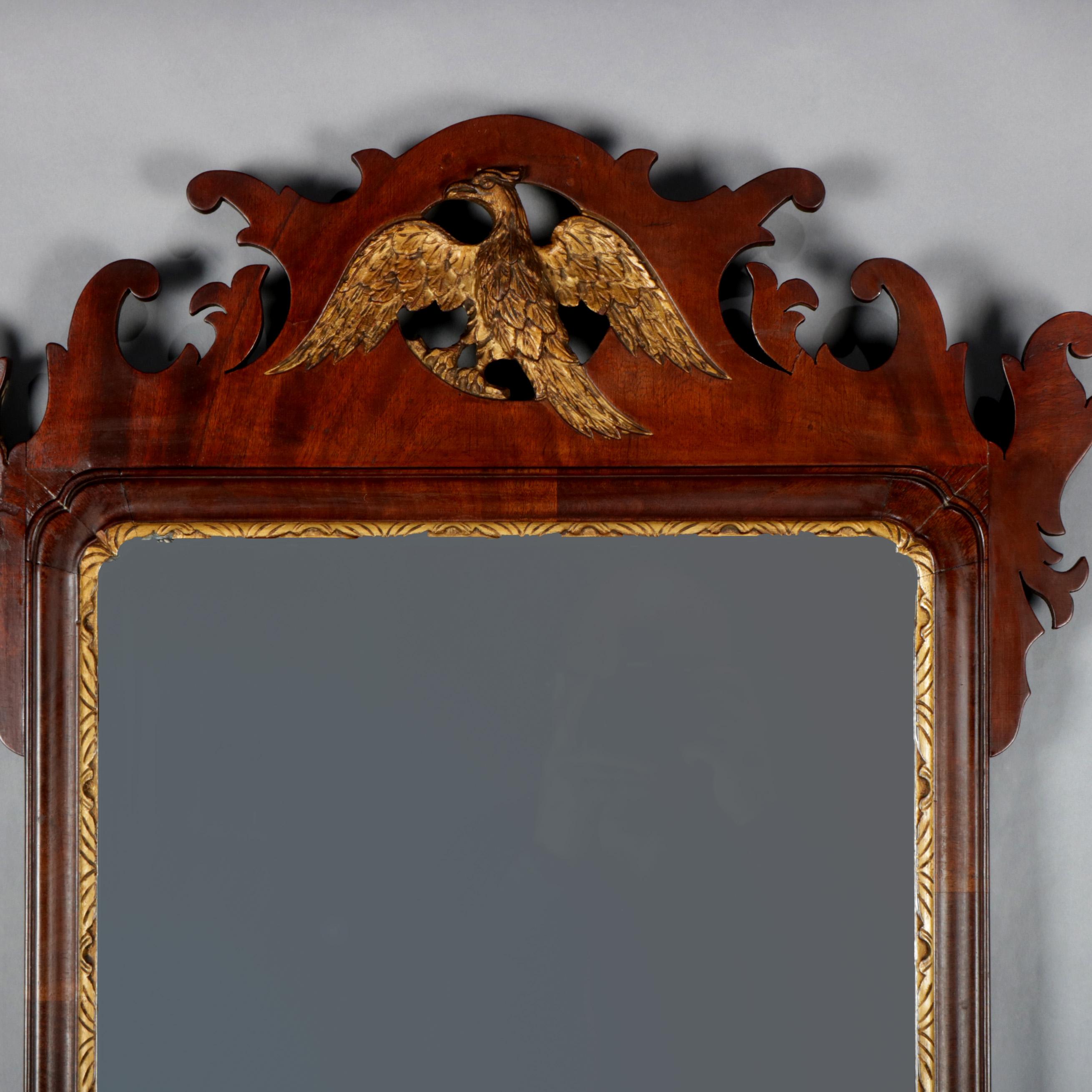 An antique Federal Chippendale wall mirror features cutout scroll form mahogany frame with pierced crest having central spread-eagle gilt phoenix and mirror plate bordered with carved foliate and gilt trim, circa 1800.

Measures: 41.5