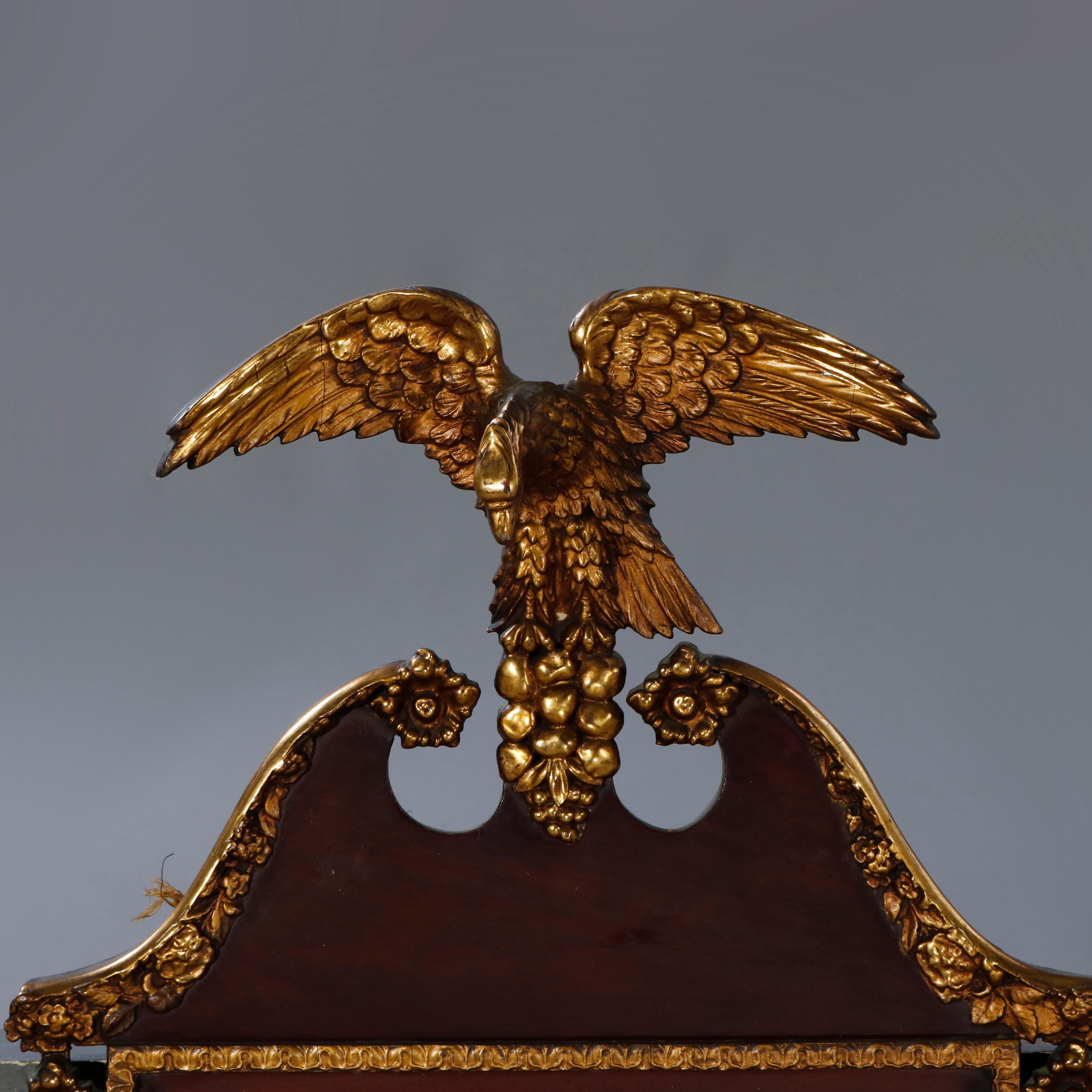 An antique Federal wall mirror offers shaped mahogany frame with broken arch pediment having giltwood figural eagle finial, flanking inverted bellflower garland, and trim, c1830

Measures: 38.75