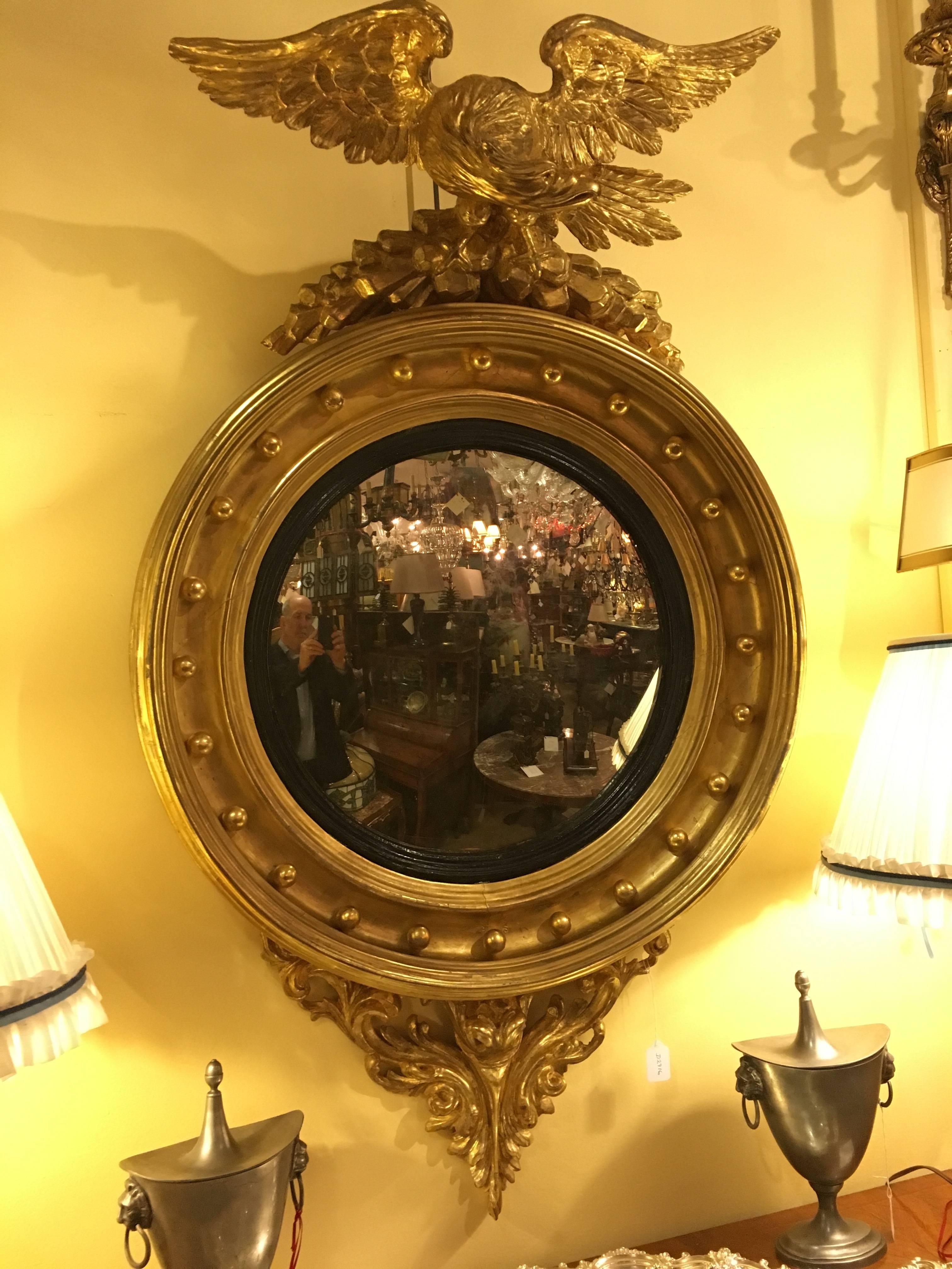 This is an outstanding example of a form much copied throughout the 19th and 20th century. It is of the period, not a copy, boldly carved with an eagle on a rocky crag, surmounting a circular mirror plate, surrounded by a gilt frame set with 26