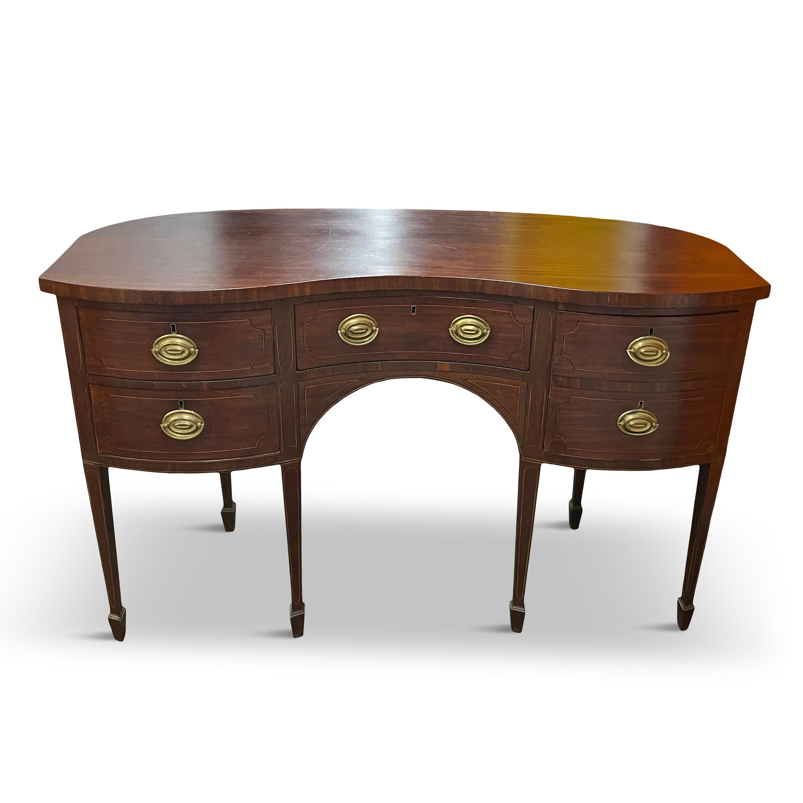This exquisite antique sideboard is a beautiful example of the Federal style, influenced by the Regency and Hepplewhite styles. It is made of a stunningly grained mahogany with a curved bow front and sides, and has a rich patina. The sideboard