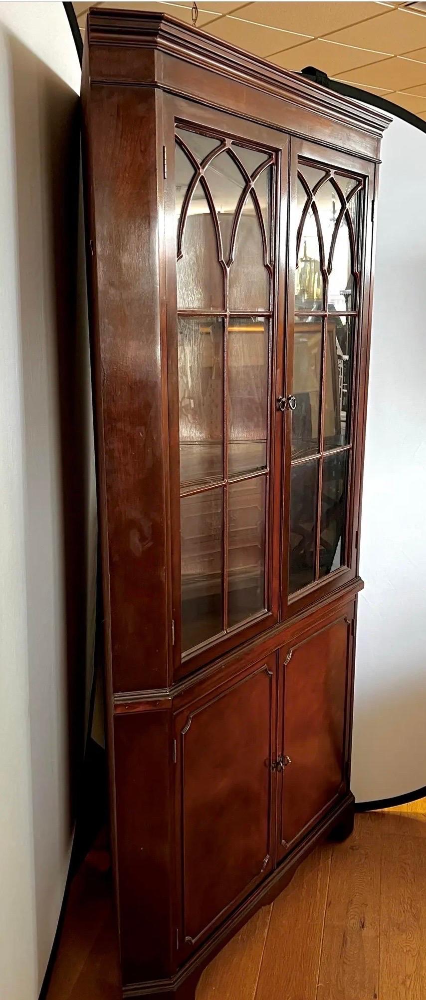 Federal style mahogany corner cabinet with glass doors that open to three fixed shelves.  Bottom section doors open for more storage. One piece construction.  Stunning bespoke corner cabinet.