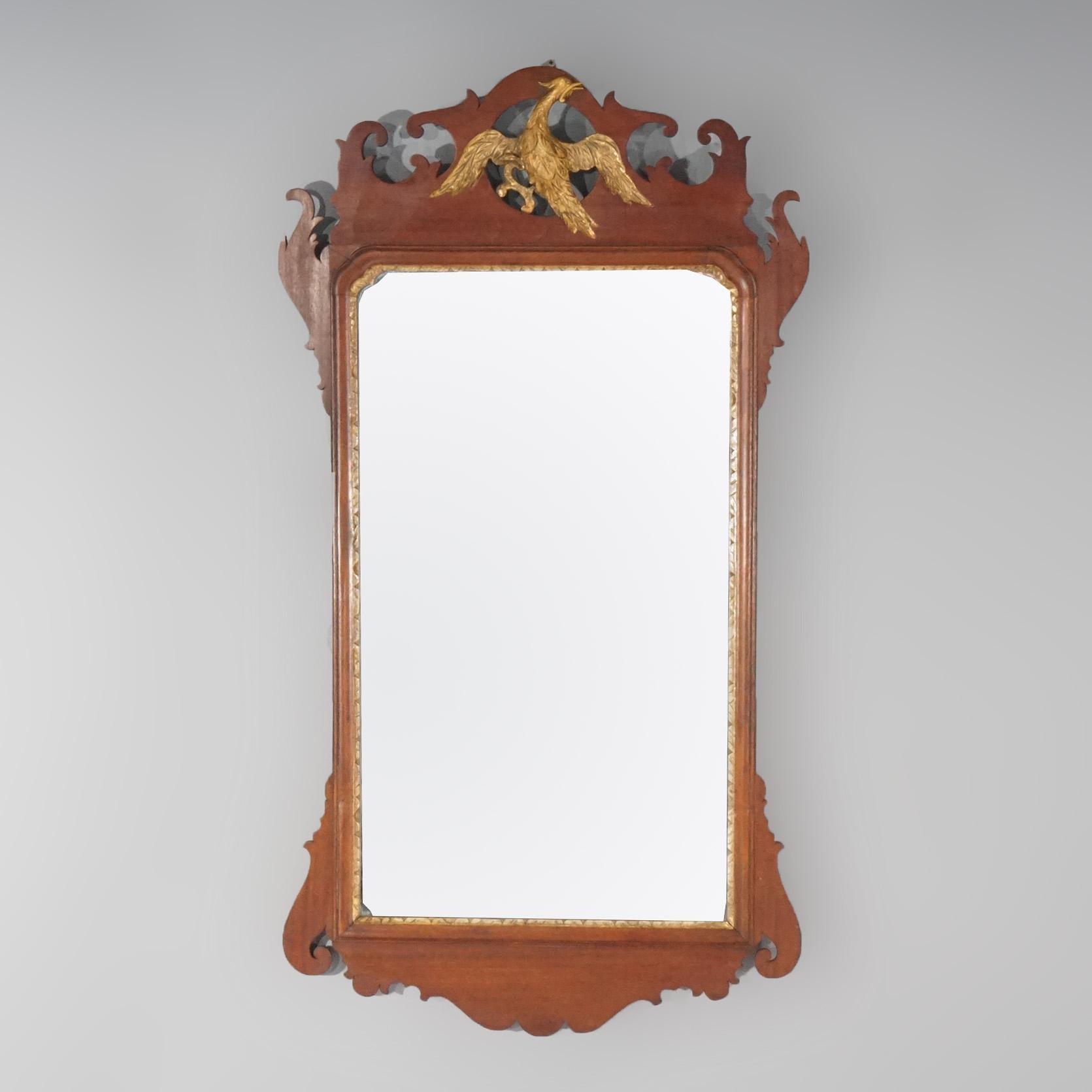 An antique figural Federal wall mirror offers mahogany construction with scroll and shaped frame having giltwood carved eagle at crest, 19th century.

Measures - 38.25