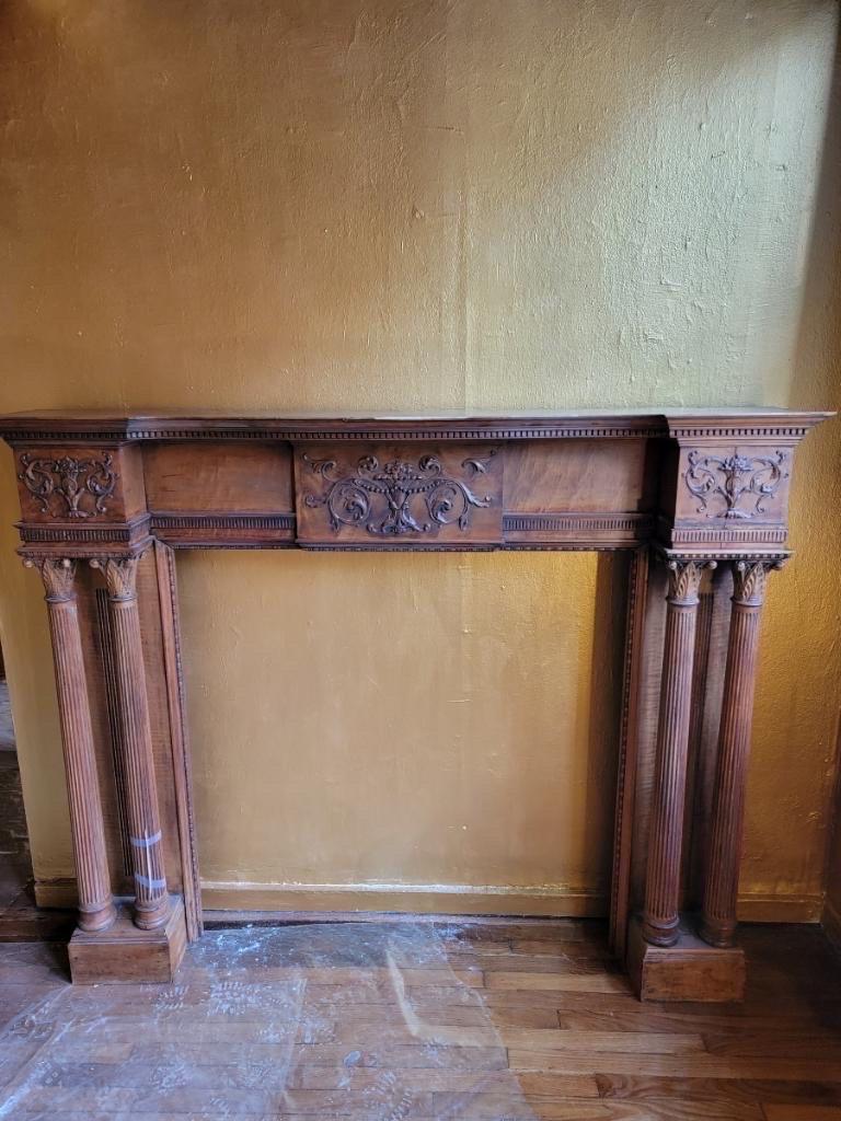Antique hand carved finely detailed Federal style fireplace surround & mantel

Antique hand-carved ornate Corinthian capitals nested atop dual flanked, thickly tapered, fluted columns. Three decorative panels provide a visual break between the