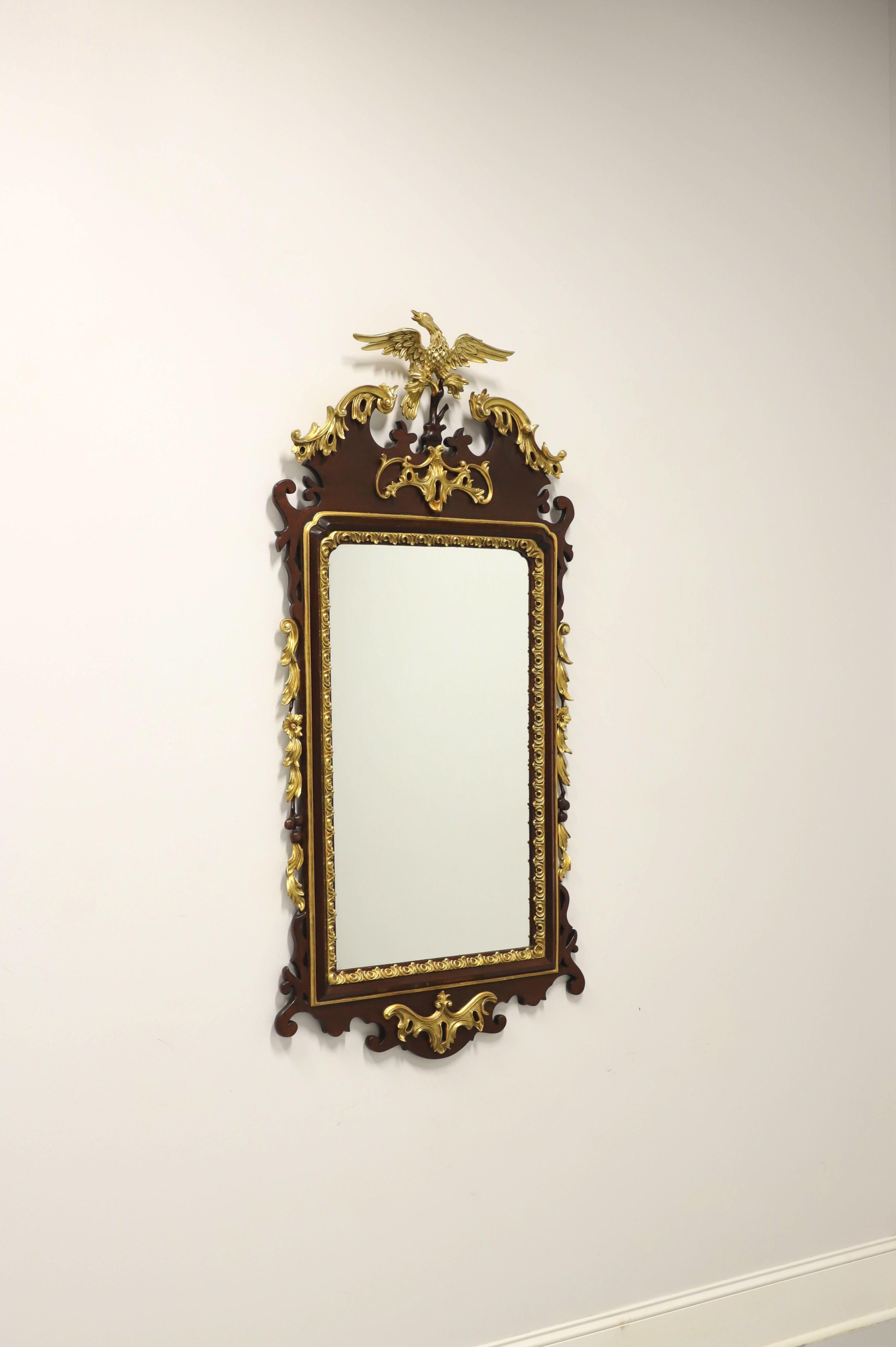An antique Federal style wall mirror, unbranded. Mirror glass in a mahogany frame with gold gilt, decoratively carved throughout, gold escutcheon ornamentation to center of top & bottom, and a pediment design with a gold eagle on a tree branch to