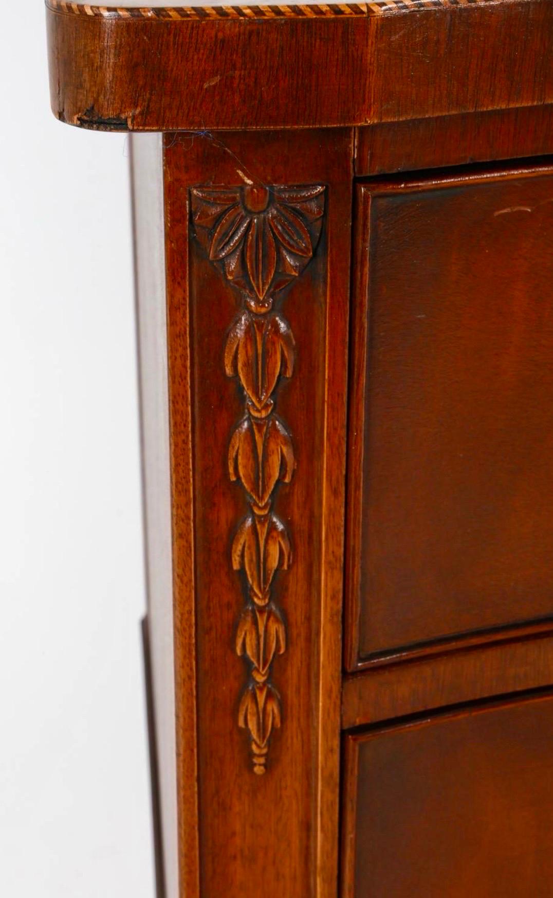 Elegante credenza Feder che presenta un frontale graziosamente curvo, completato da una ferramenta in ottone ornata che accentua la ricca finitura in mogano.  I suoi sei cassetti a coda di rondine offrono una generosa quantità di spazio per riporre