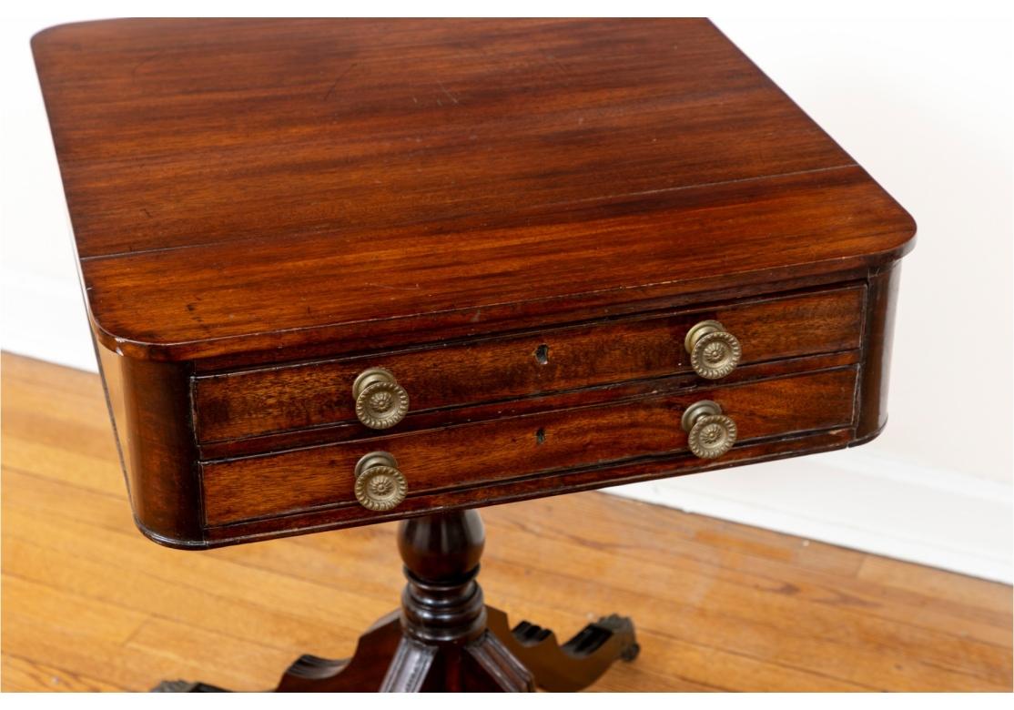 Table d'appoint ancienne en acajou de style Feder avec deux tiroirs de travail peu profonds sur le devant et des faux tiroirs au verso, chacun avec deux boutons en laiton. Le coffret repose sur un piédestal tourné, de forme balustre, doté de quatre