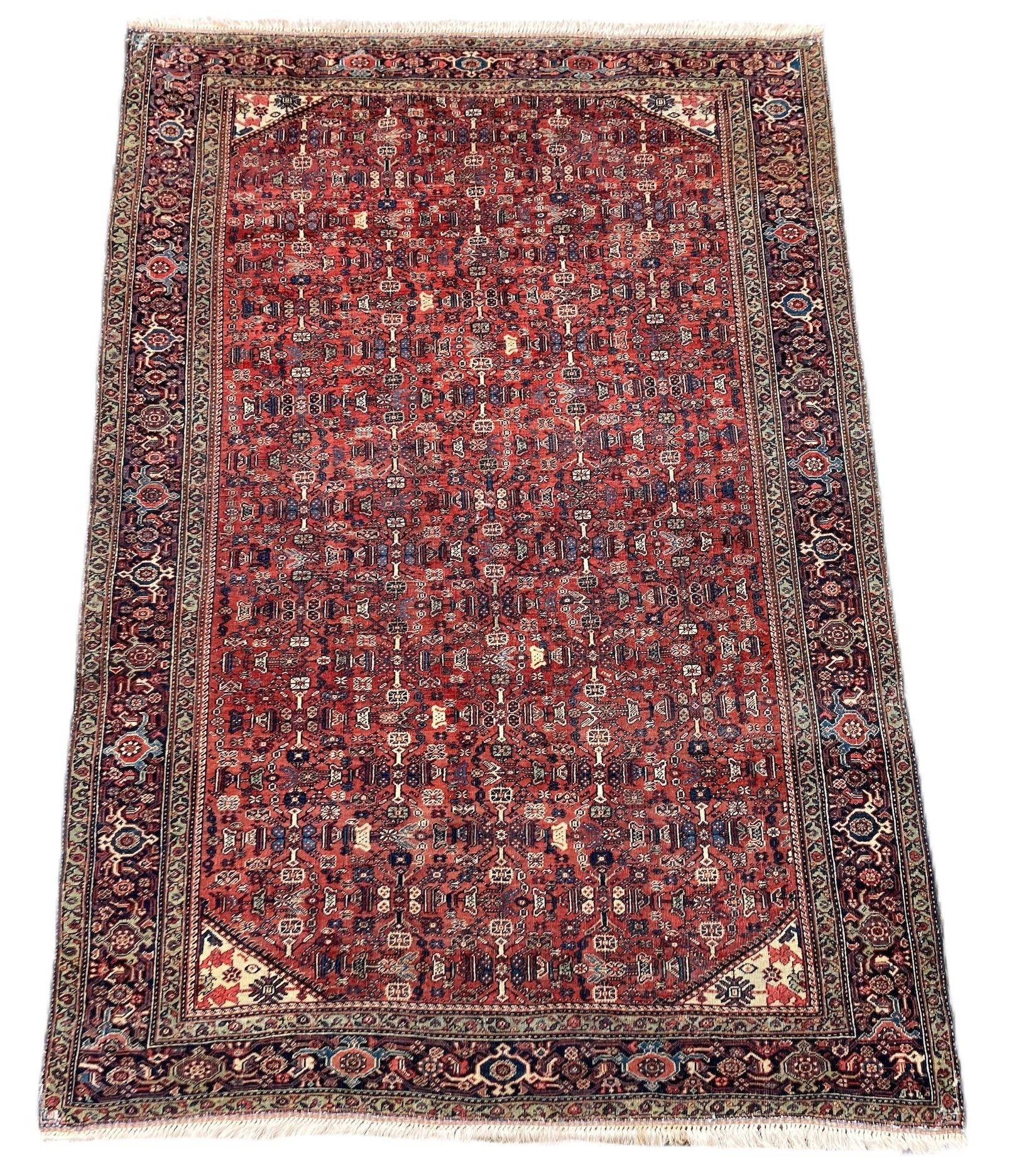 A lovely antique Ferahan rug, hand woven circa 1910 featuring an all over geometrical design of stylised flowers and vines on a terracotta field and indigo border. Finely woven with great secondary colours, particularly the green in the minor