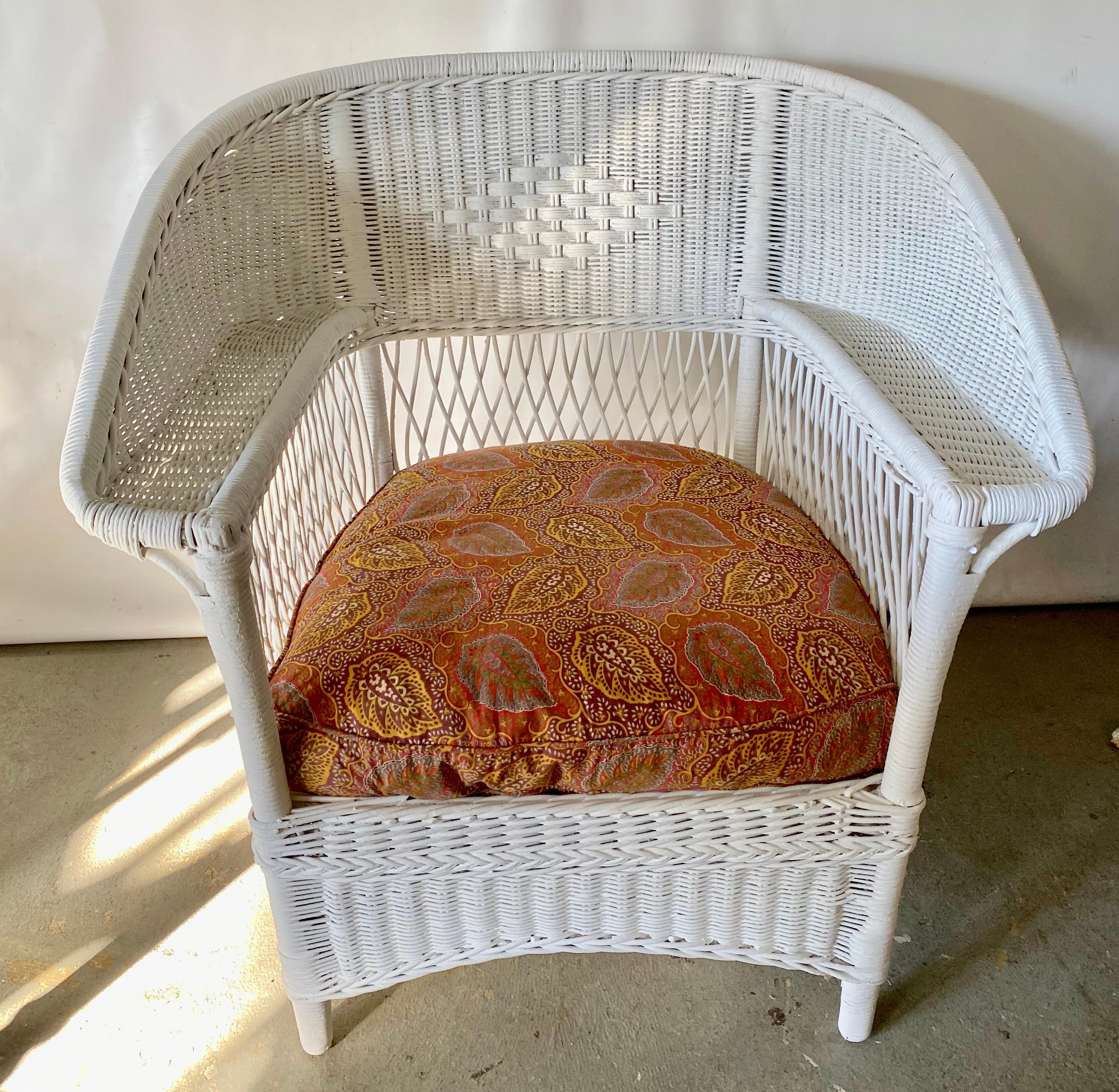 Antique Ficks Reed wicker armchair in fresh white paint has closely woven pattern, open lattice work under the arms. The fan back chair is fully skirted for tailored look on all sides. The Deco period chair has a drop in cushion on to a spring base