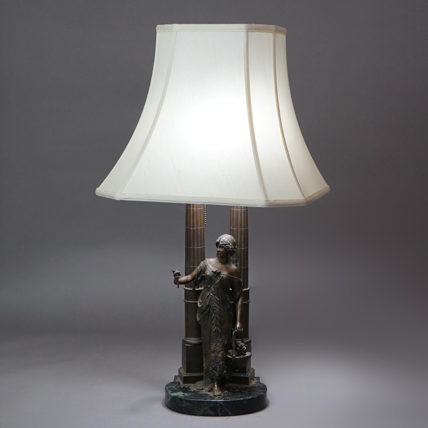 An antique figural table lamp offers bronzed cast metal construction with Classical woman standing among Corinthian columns, seated on marble plinth, c1910

Measures - 29