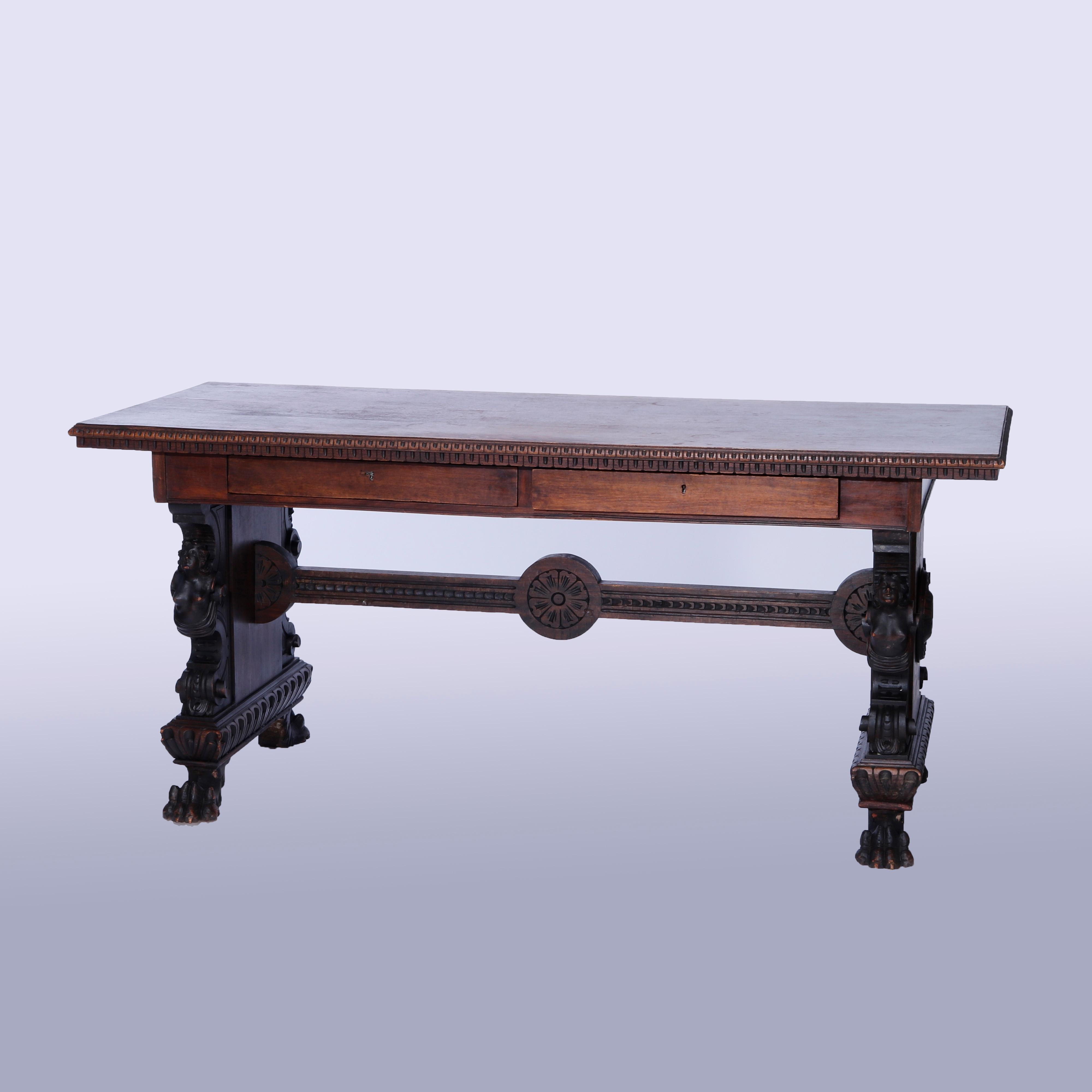 An antique figural library table offers carved walnut construction with beveled top having stylized dental bordering over double drawers raised on trestle legs with female caryatids, stylized rosette medallions and paw feet, c1900

Measures -