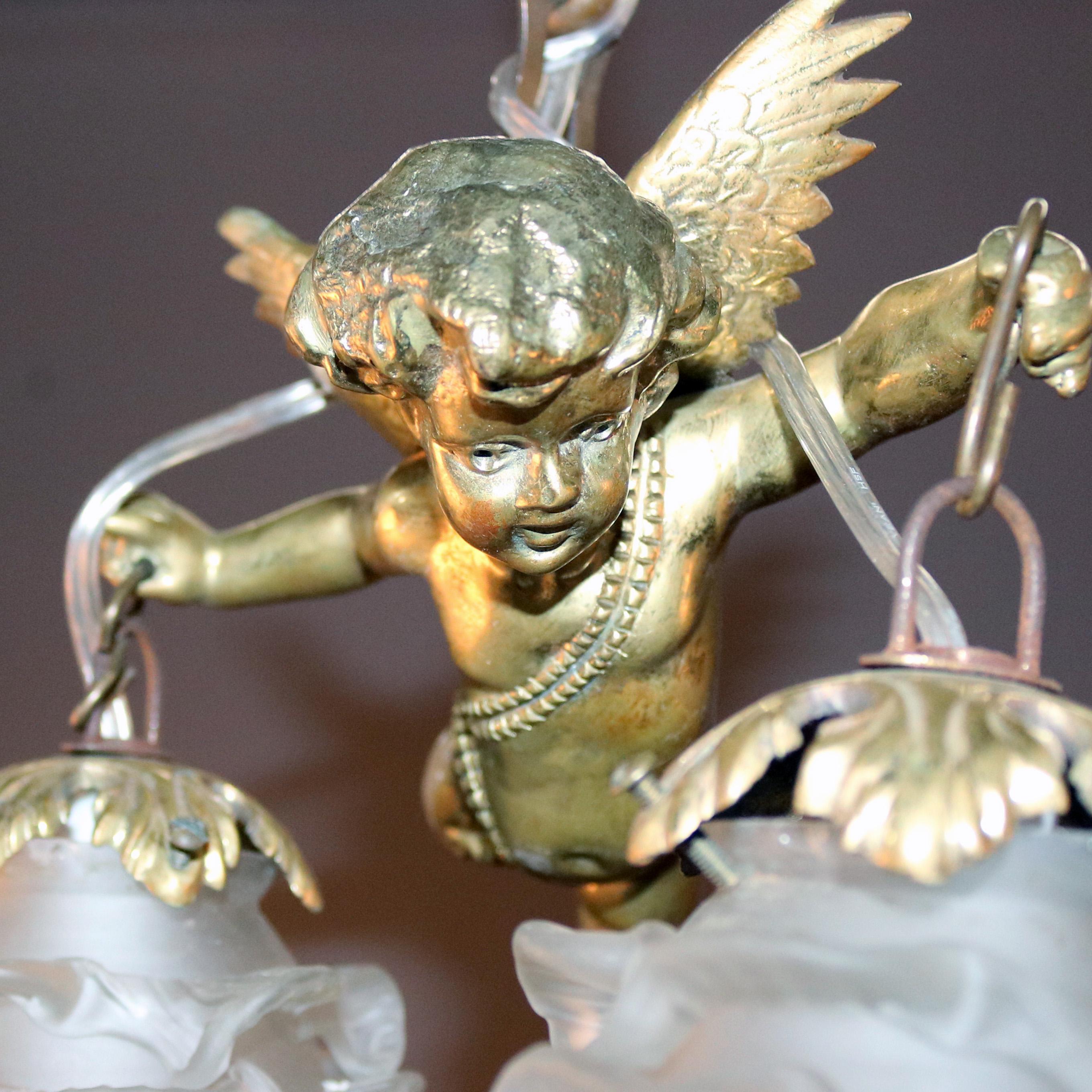 An antique figural gilt bronze hanging light fixture features cherub in flight holding foliate drop light in each hand with frosted glass floral form shades, circa 1920.

Measures: 17.5” H x 8.4” D.