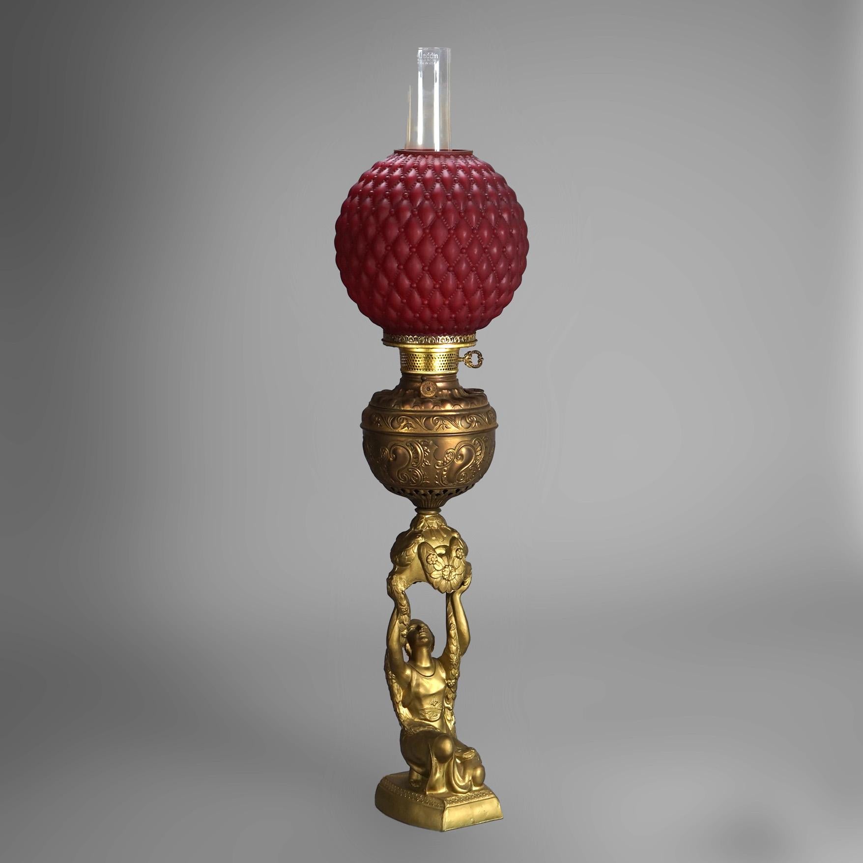An antique figural parlor lamp offers quilted ruby satin glass shade over gilt cast metal base having a foliate embossed font and kneeling woman, electrified, c1900

Measures - 34.5