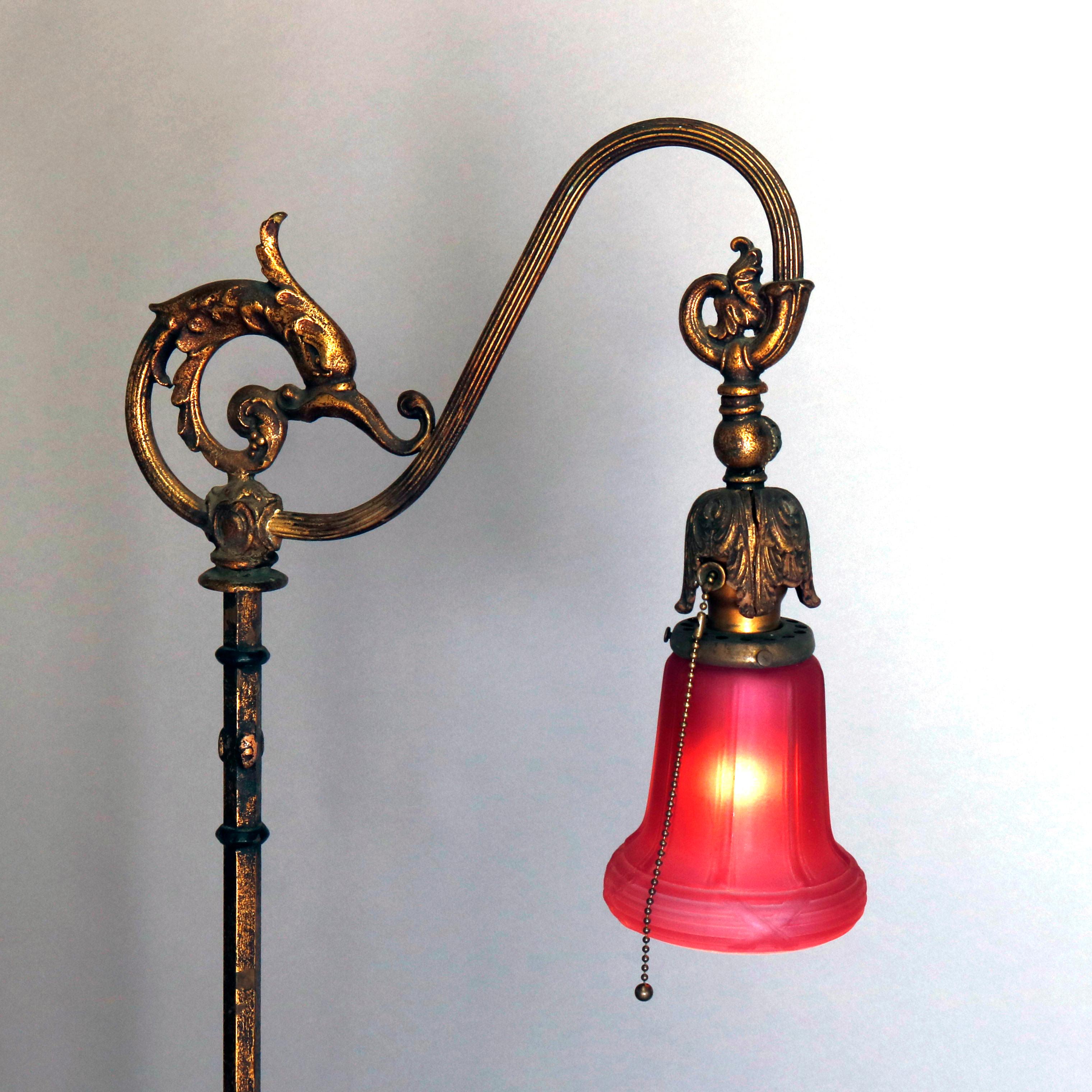 An antique figural floor lamp offers metal frame with dolphin and goose neck arm terminating in art glass shade, raised on decorated pole with tripod foliate base, circa 1920.

 Measures: 59.25