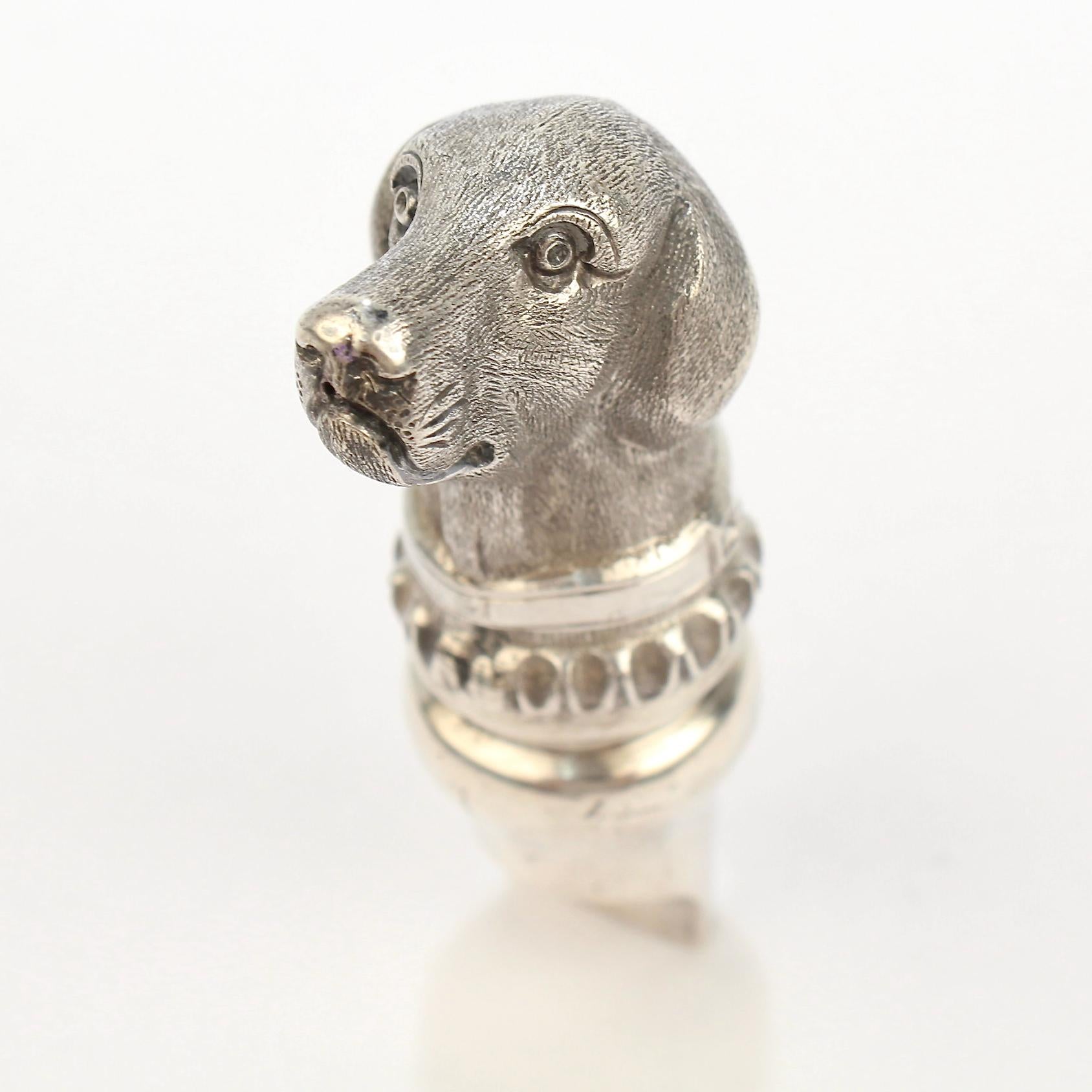 An extraordinarily fine figural dog whistle.

In sterling silver in the form of a retriever. The back is a functional whistle.

The top is set with a bail and jump ring so that it can be worn as a pendant for a necklace (and was likely suspended