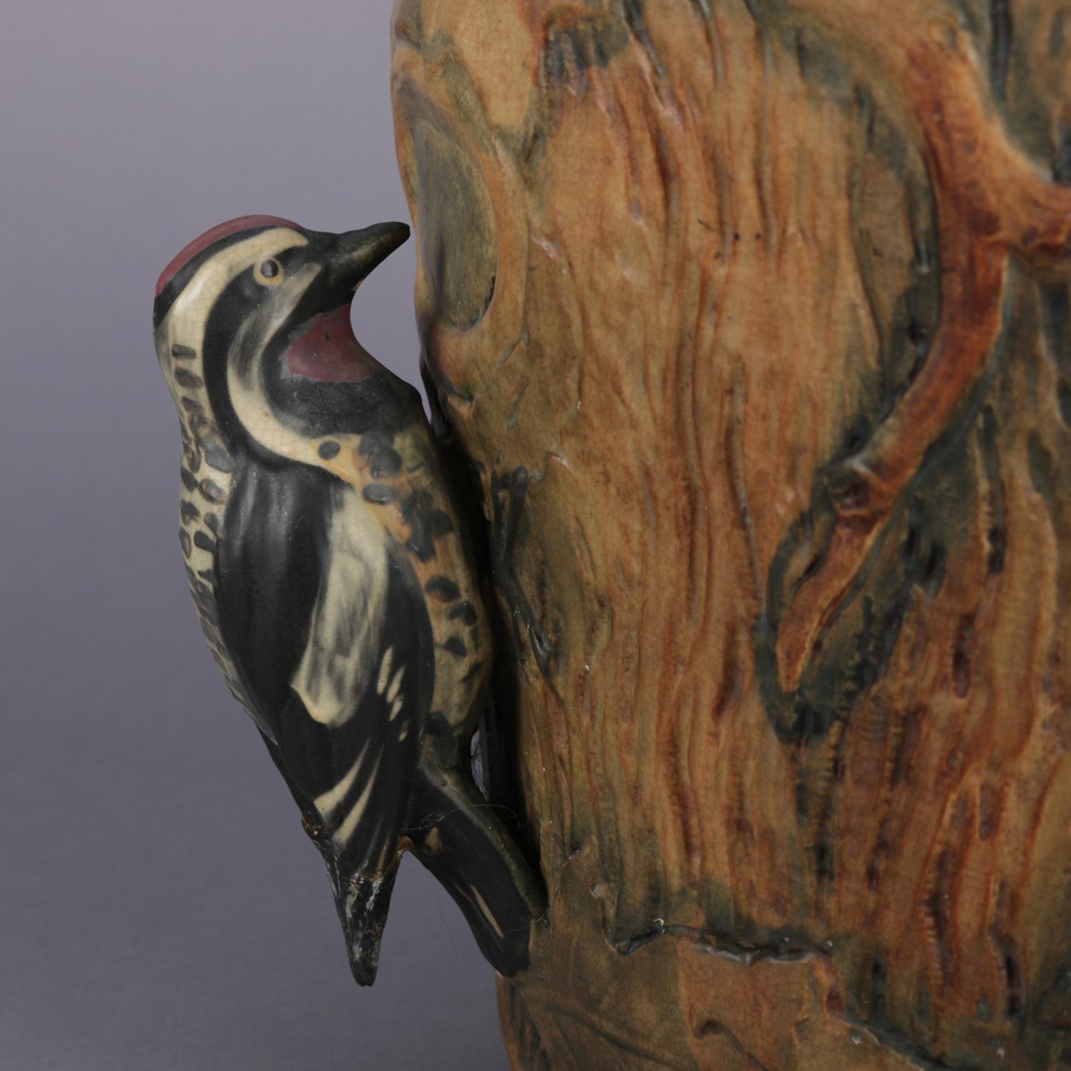 Antique figural art pottery jardiniere urn features high relief tree trunk form having oak leaves and acorns with applied woodpecker and squirrel figures on opposing sides, circa 1920,

Measures: 9.5