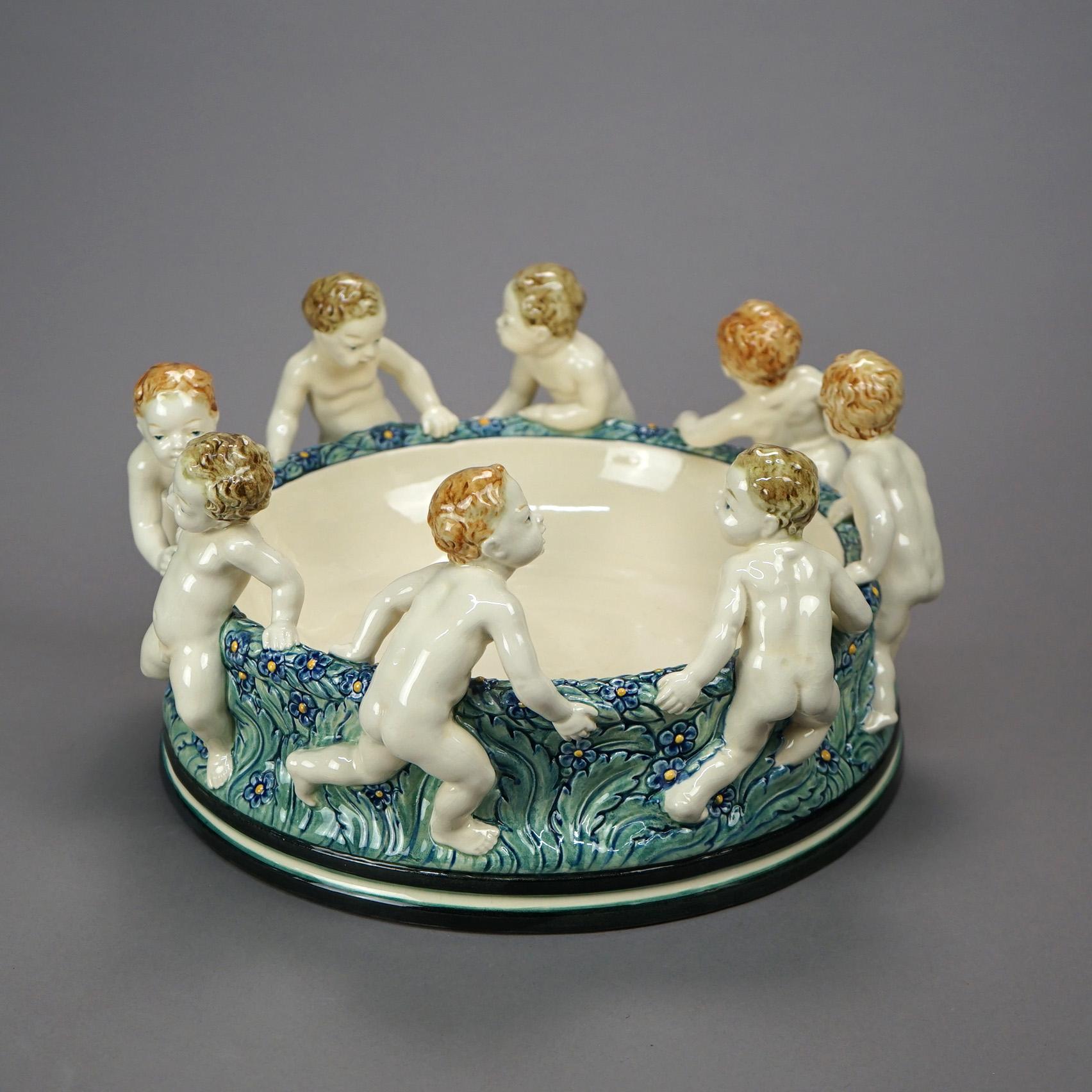 A large antique figural Wilhelm Majolica center bowl offers ceramic construction with dancing cherubs, maker marks as photographed, c1900

Measures- 6.75''H x 12.75''W x 12.75''D.
