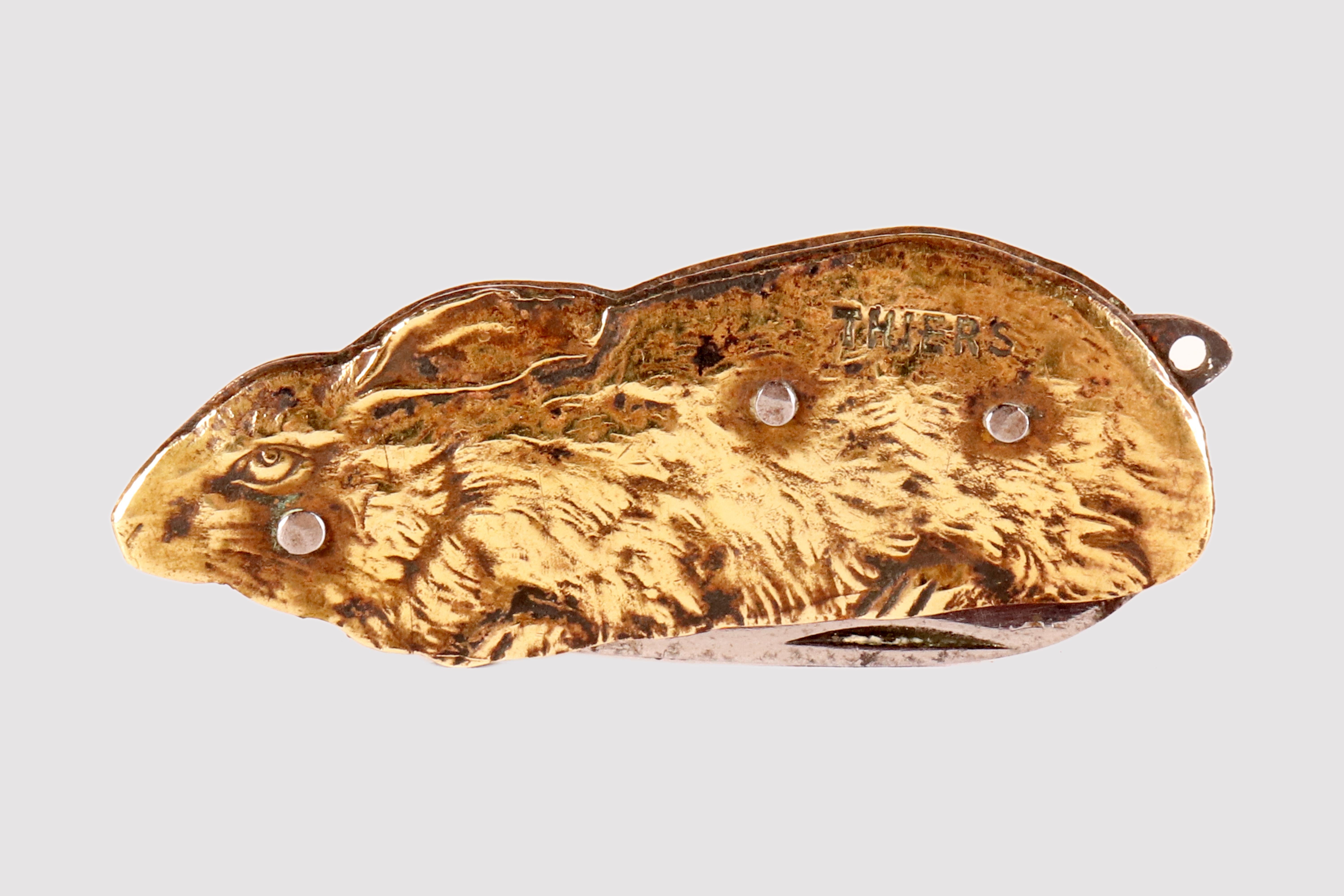 Antique figurative pocket knife, chiseled and guilloché, representing a rabbit lying down with its ears down. Brass handle plates with three rivets, spring and steel blade. Signed Thiers. France, period beginning 20th century, circa 1920.
