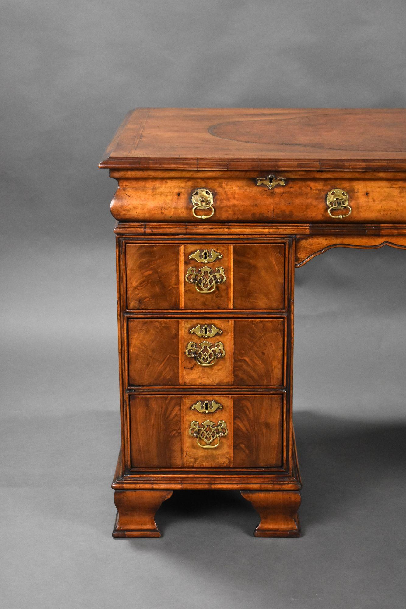 For sale is a good quality antique figured walnut desk, having a shaped, hand coloured leather hide writing surface, above two long drawers in the top, with a further three short drawers in each pedestal, all with original brass handles. The desk