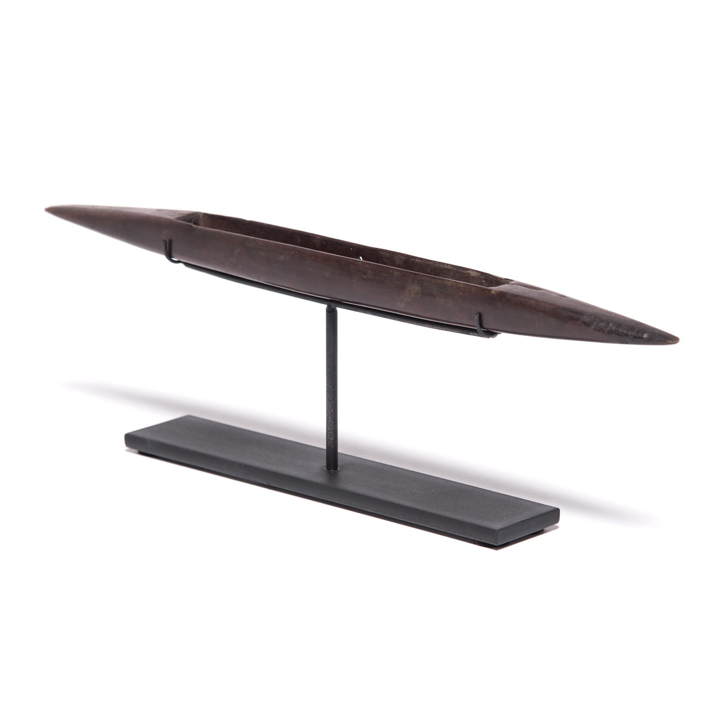 We’ve mounted this vintage wood weaving shuttle from the Philippines on a custom metal stand to highlight its sleek, sculptural form. Designed as a tool for an expert weaver, the late 19th century shuttle was used to carry weft yarns of spun silk