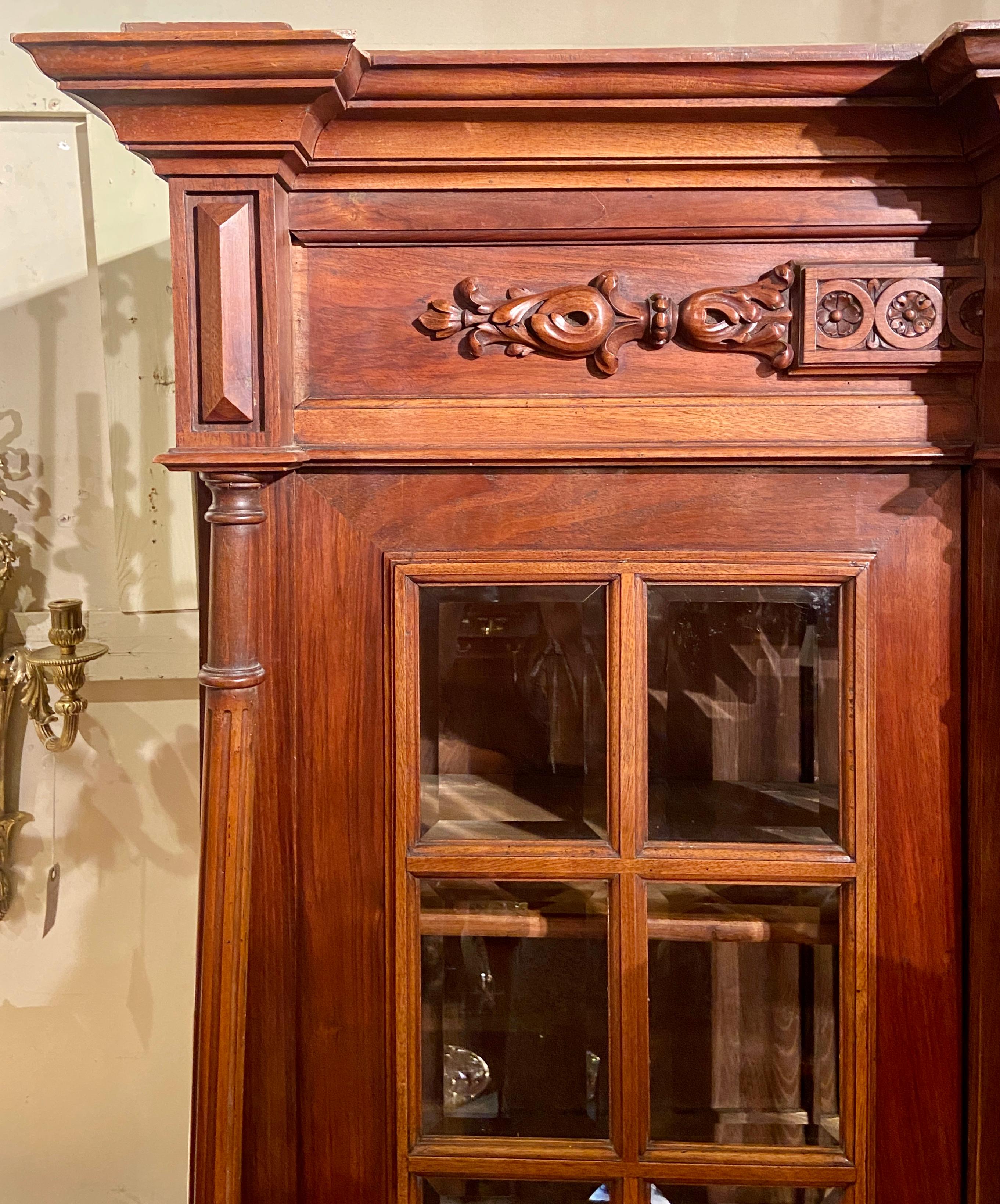 Antique finely carved walnut bookcase with beveled glass front.